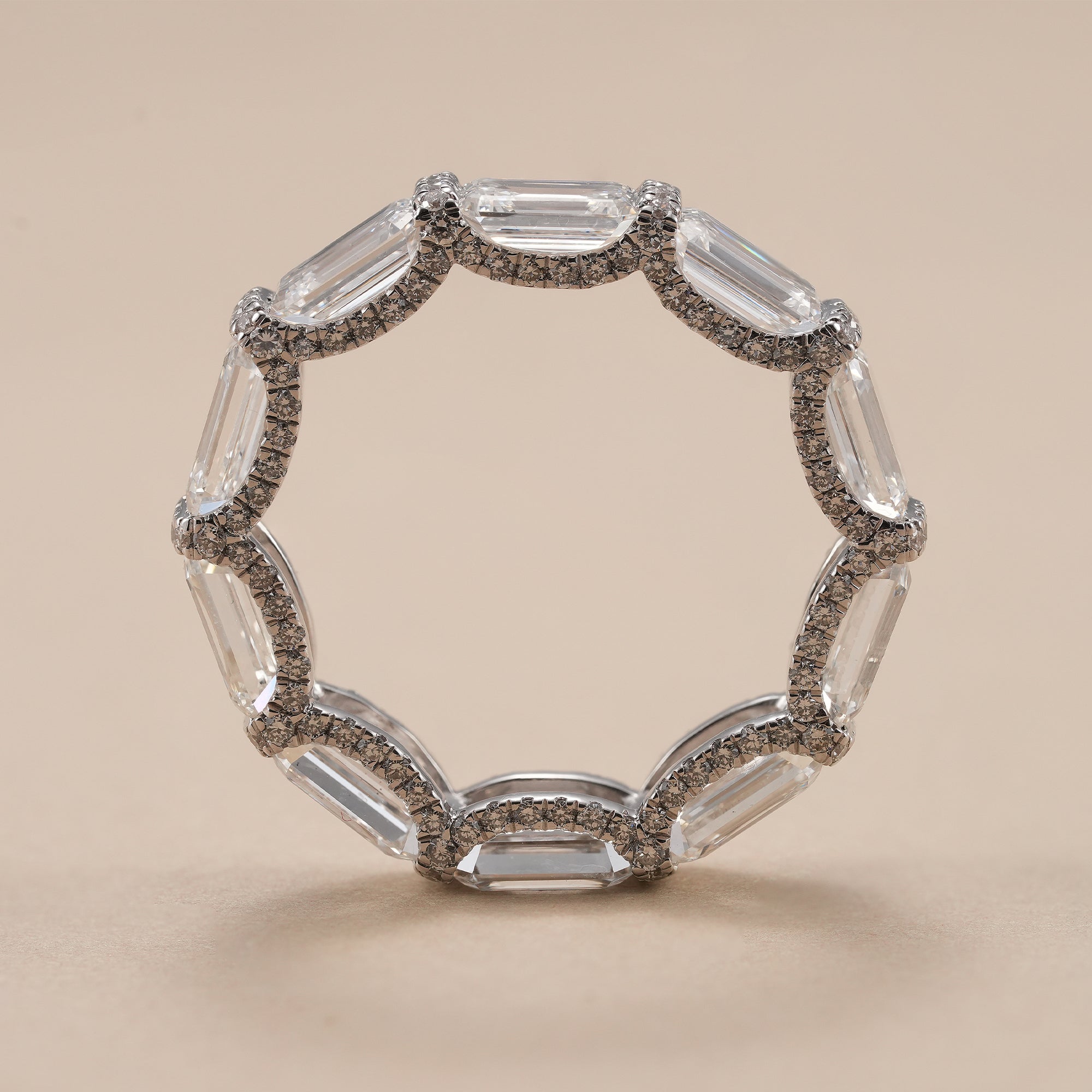 Emerald diamond eternity ring with pavé halo setting.