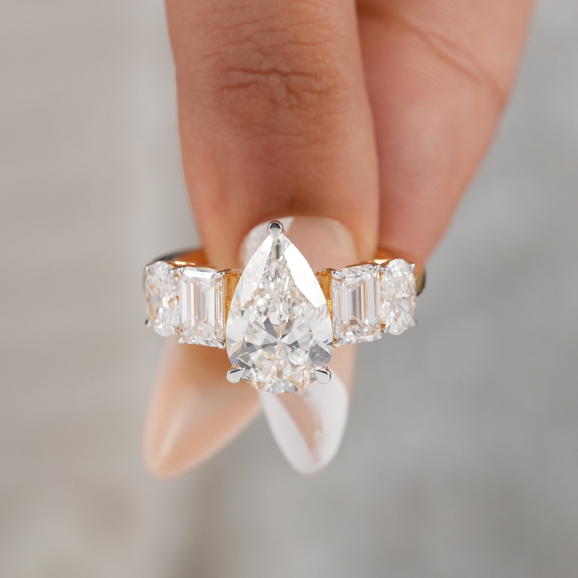 Three carat pear diamond ring featuring five stone design.