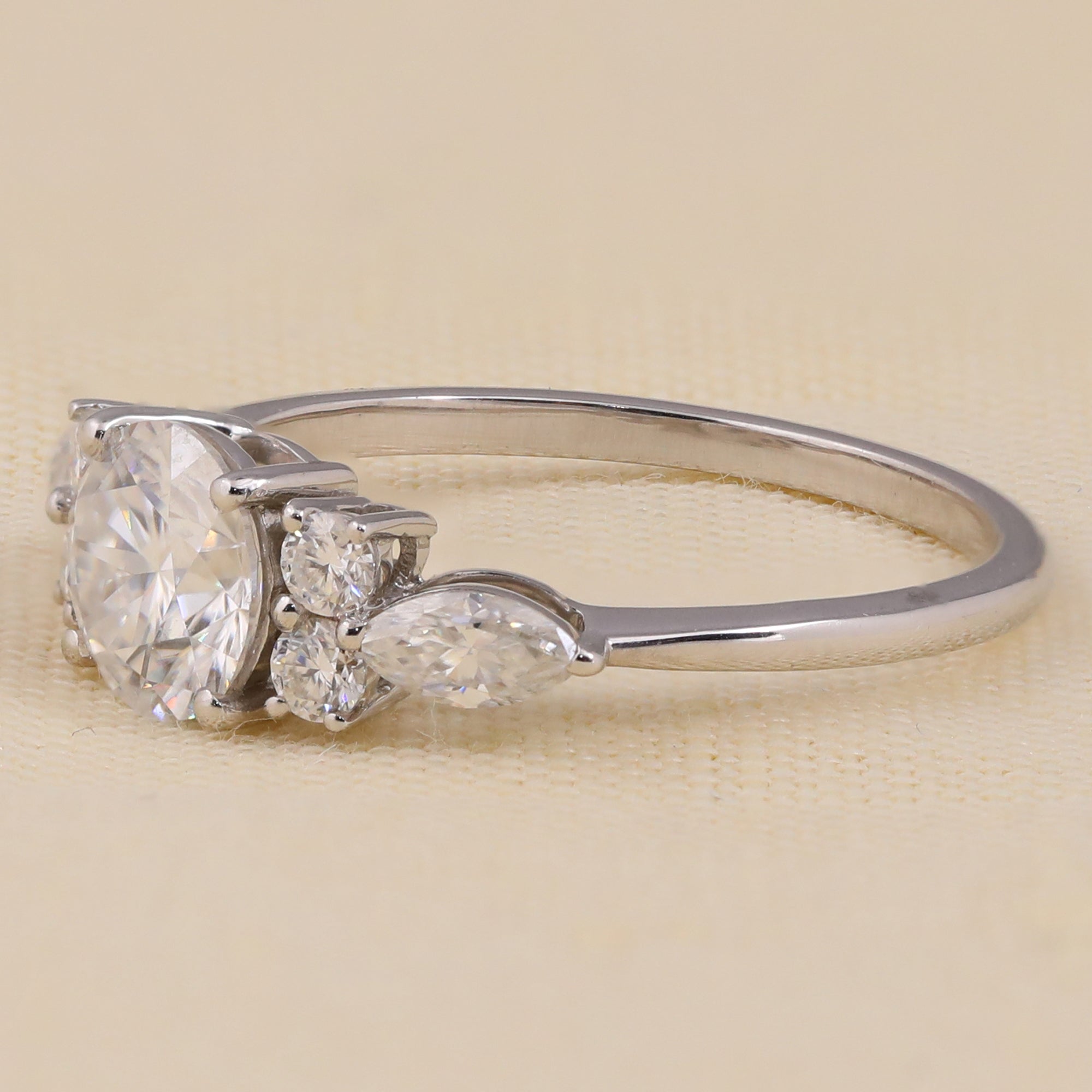 Round cut lab diamond engagement ring with cluster side stones for bridal jewelry.