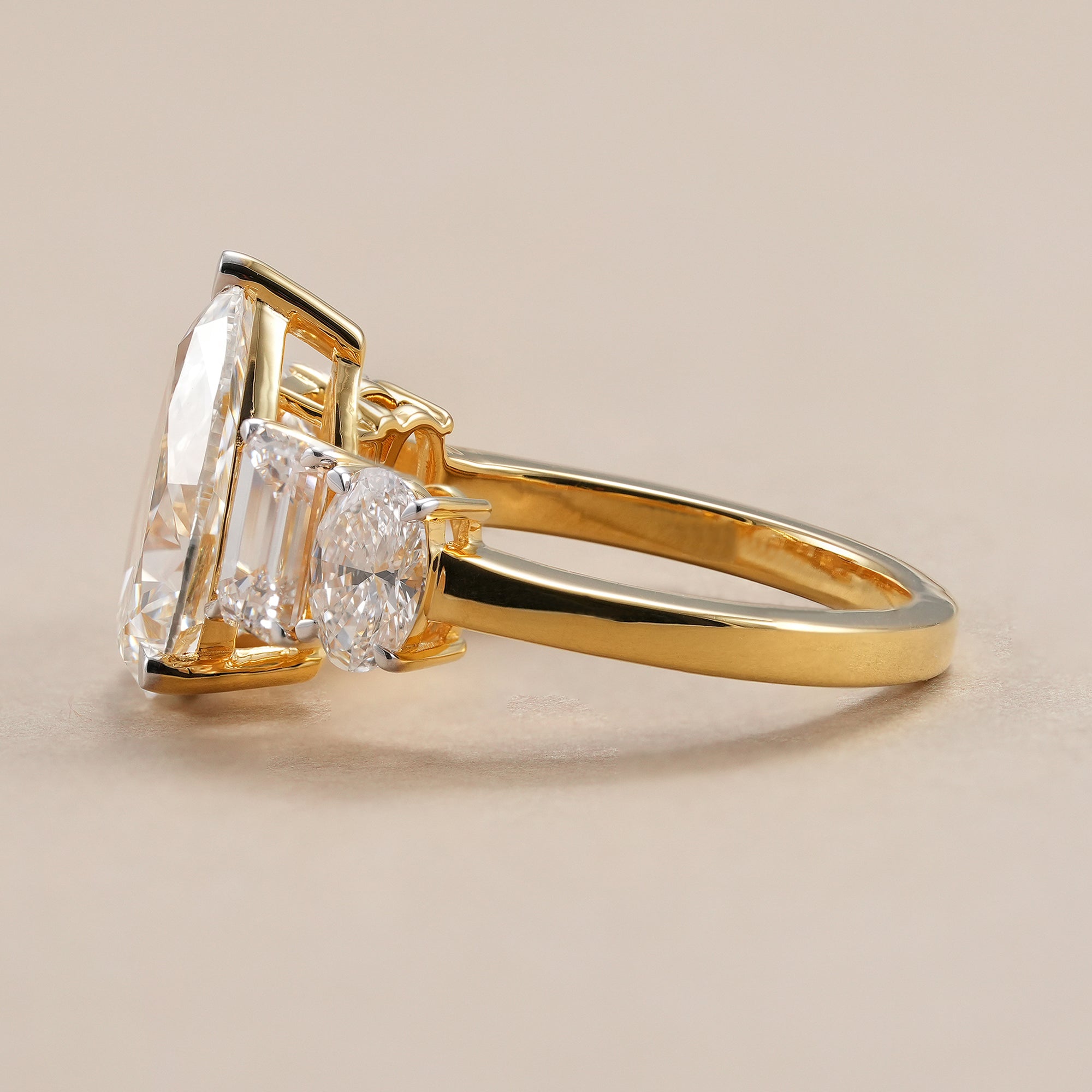 Five stone pear lab diamond engagement ring with emerald accents.