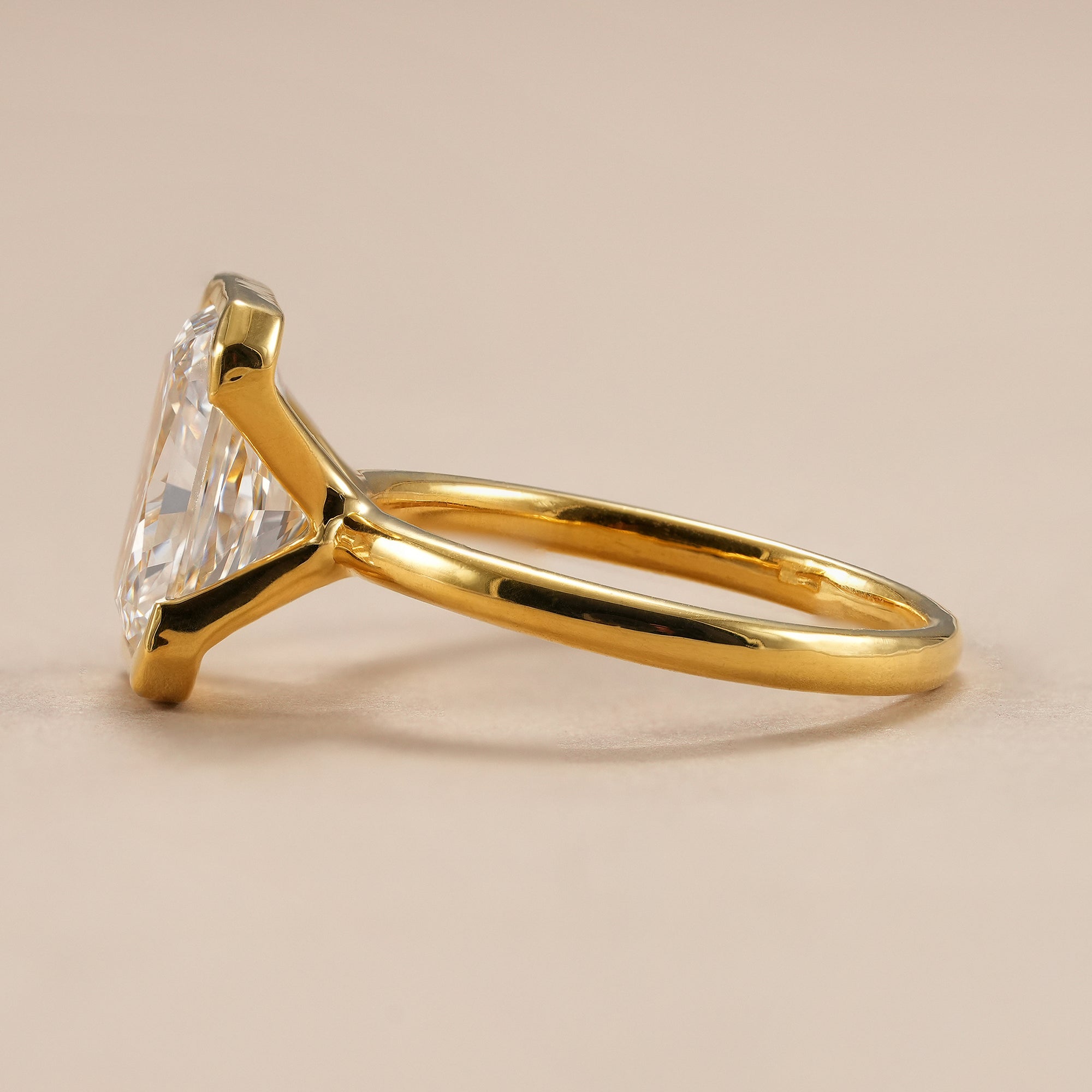 Modern half bezel radiant diamond ring with minimalist yellow gold band.