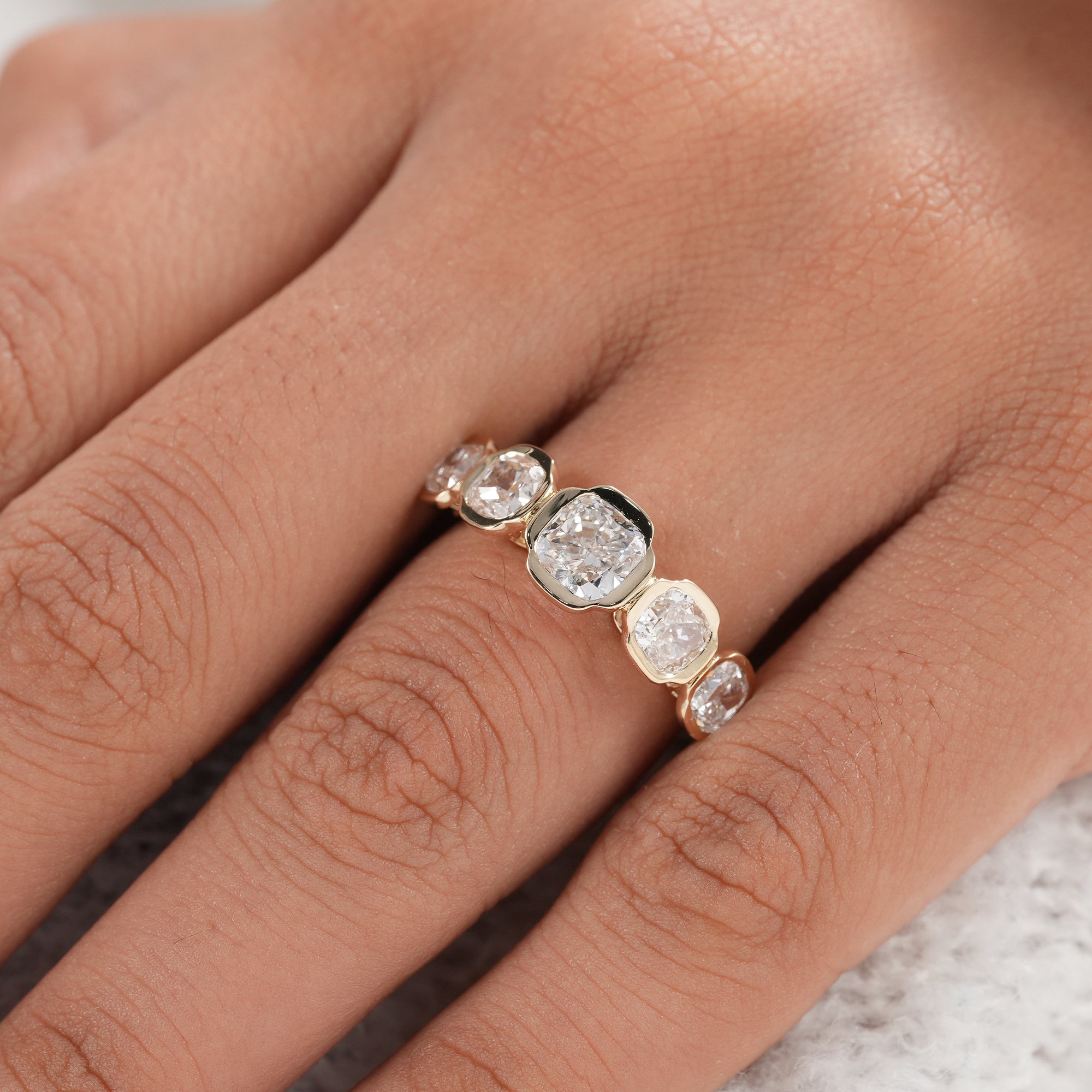 Modern lab grown diamond wedding band with five bezel set stones.