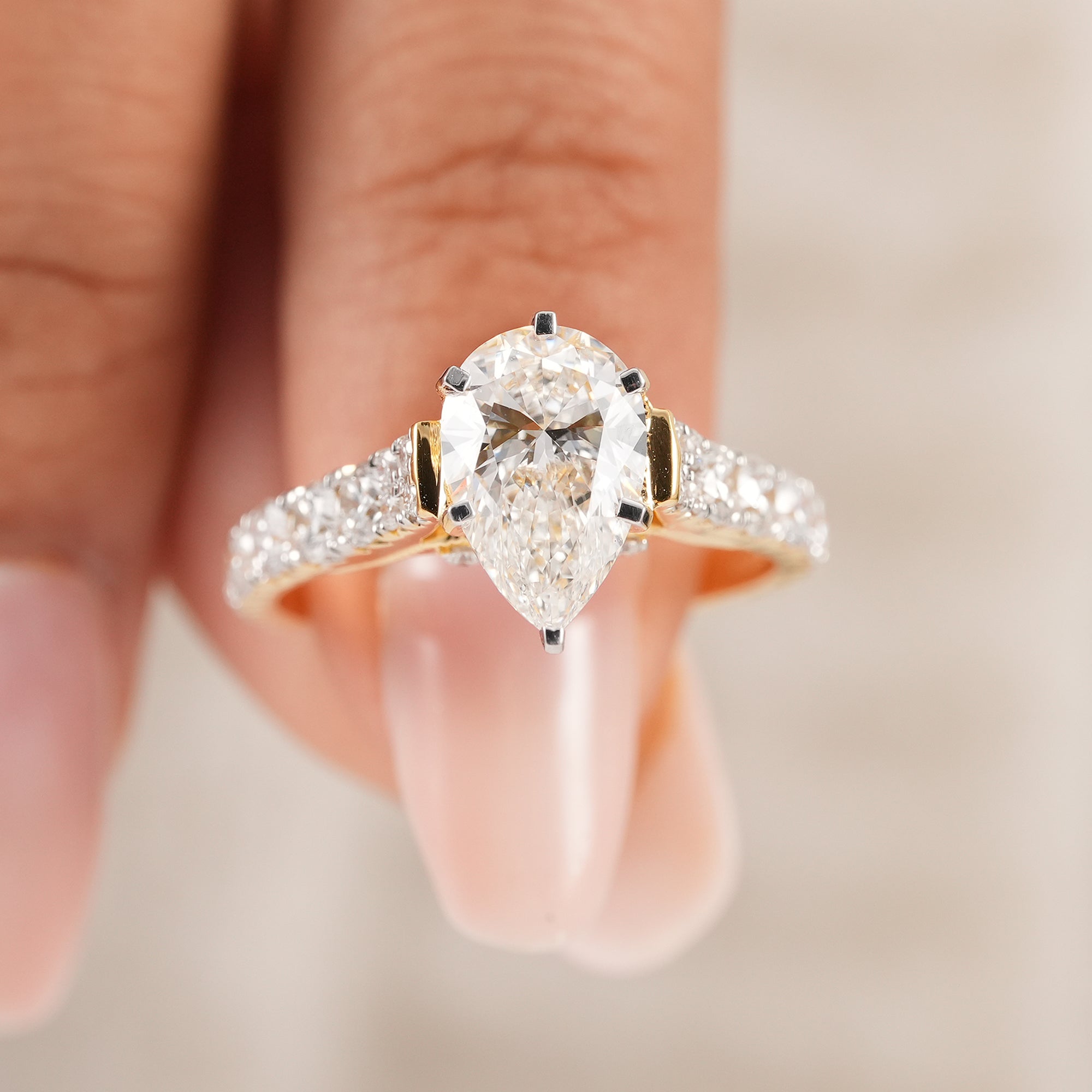Pear diamond ring featuring cathedral setting and pavé diamond band