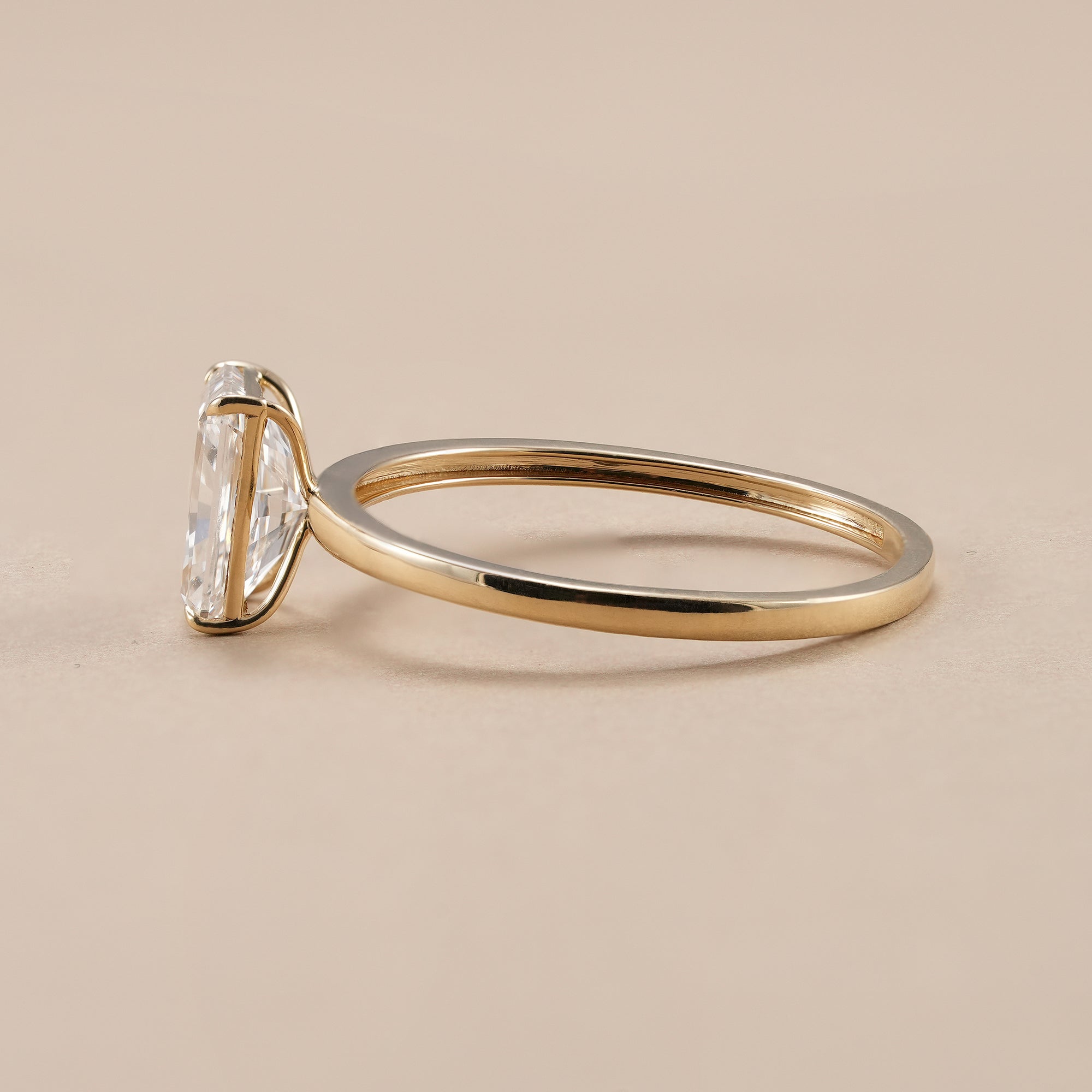 Four prong radiant diamond engagement ring with polished gold band.