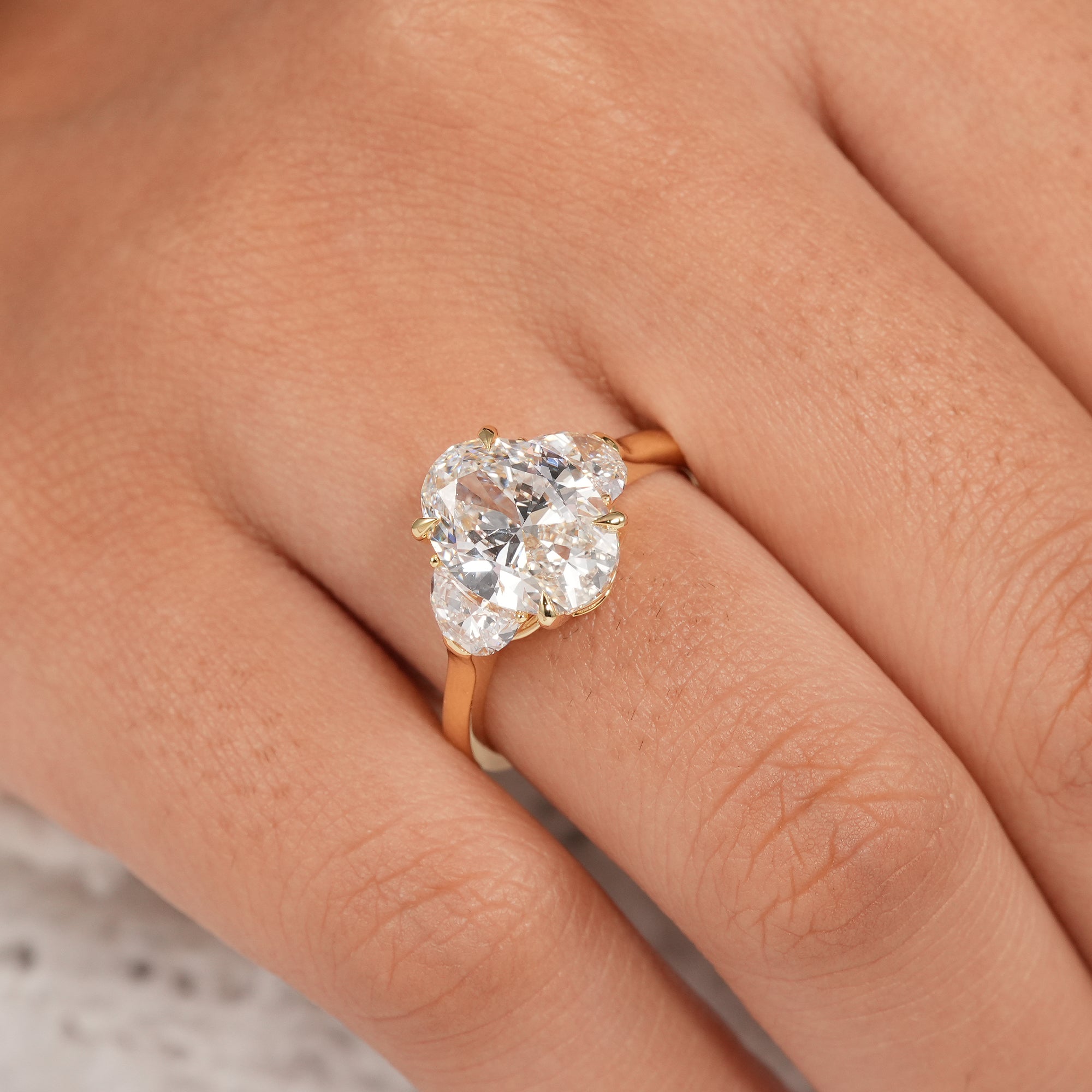 Oval cut lab grown diamond ring with half moon side stones and polished gold band