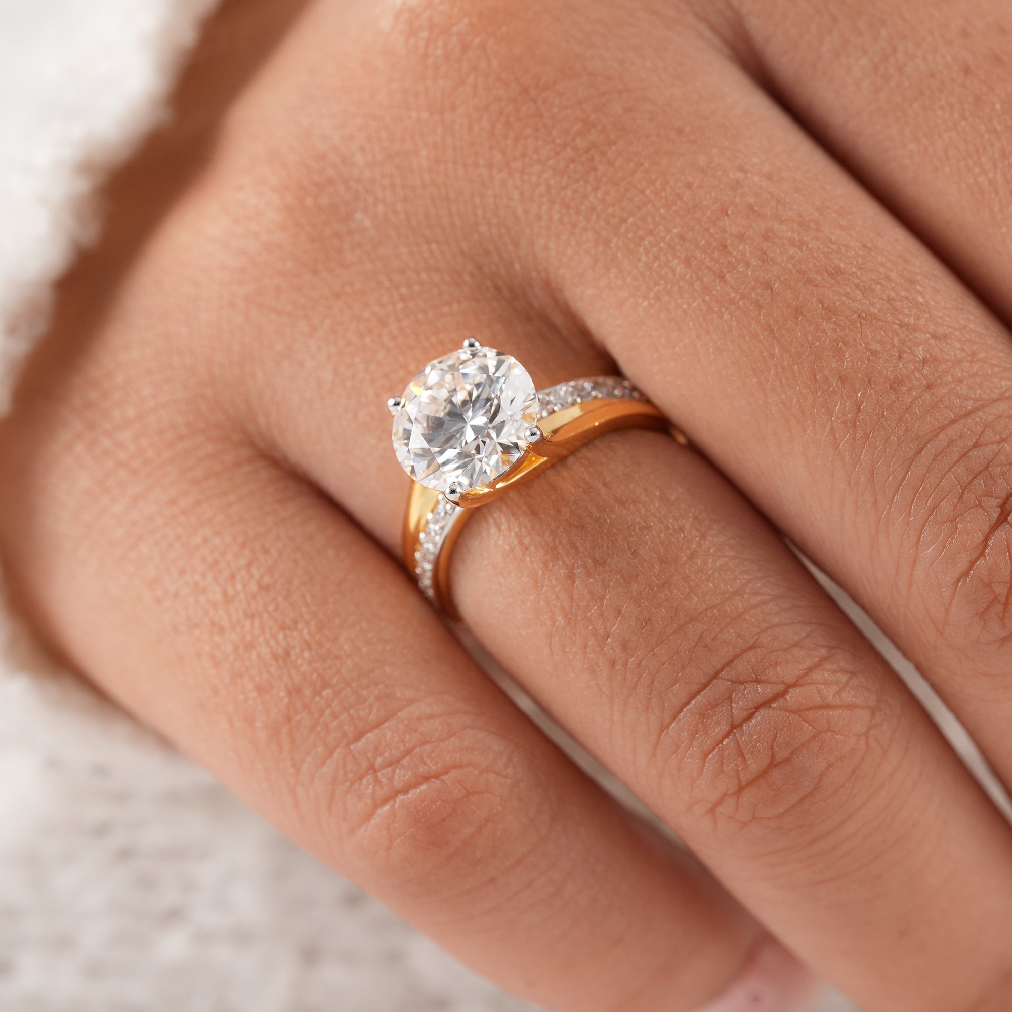 Four prong round solitaire engagement ring featuring pavé diamonds