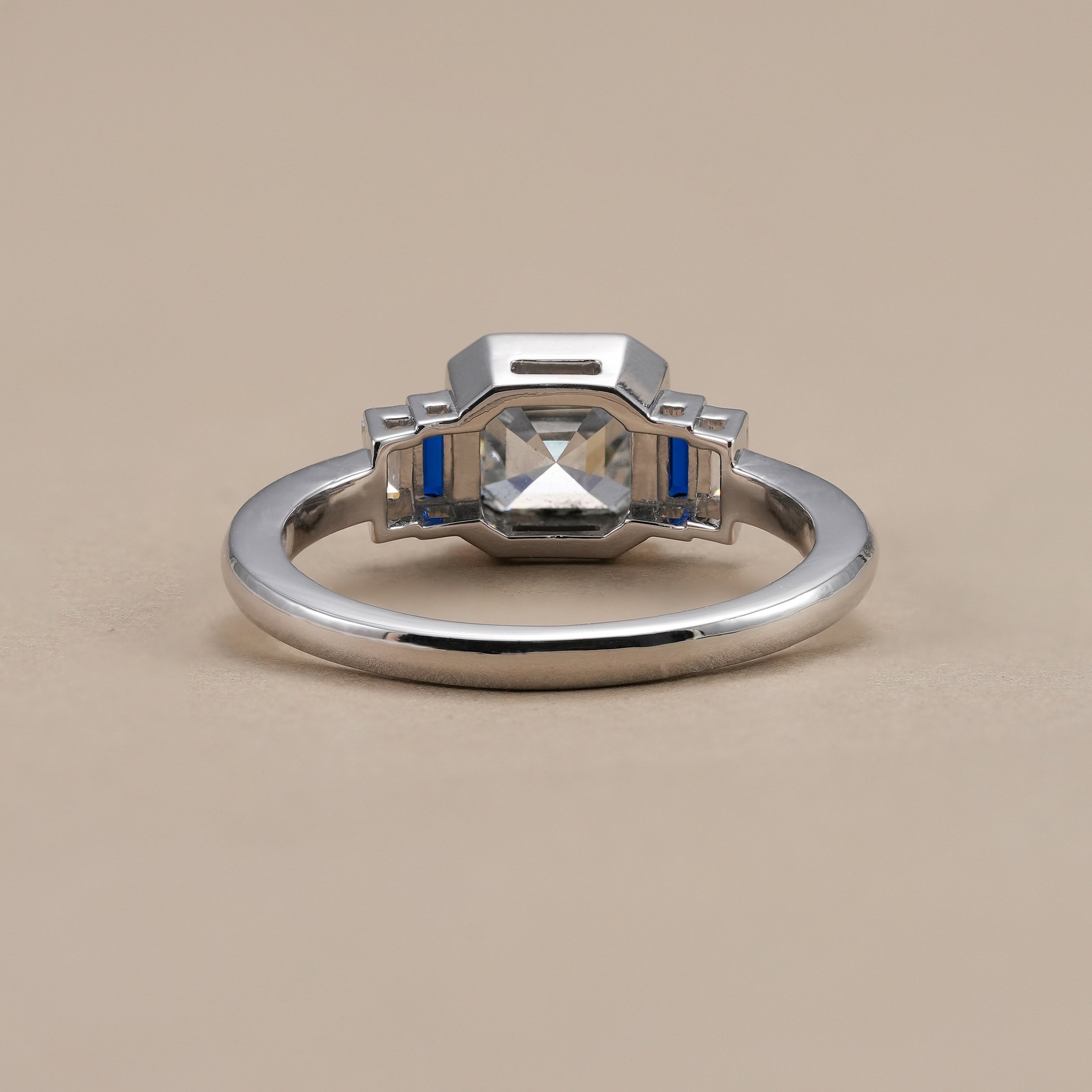 Asscher cut bezel set diamond ring with white baguette side stones.