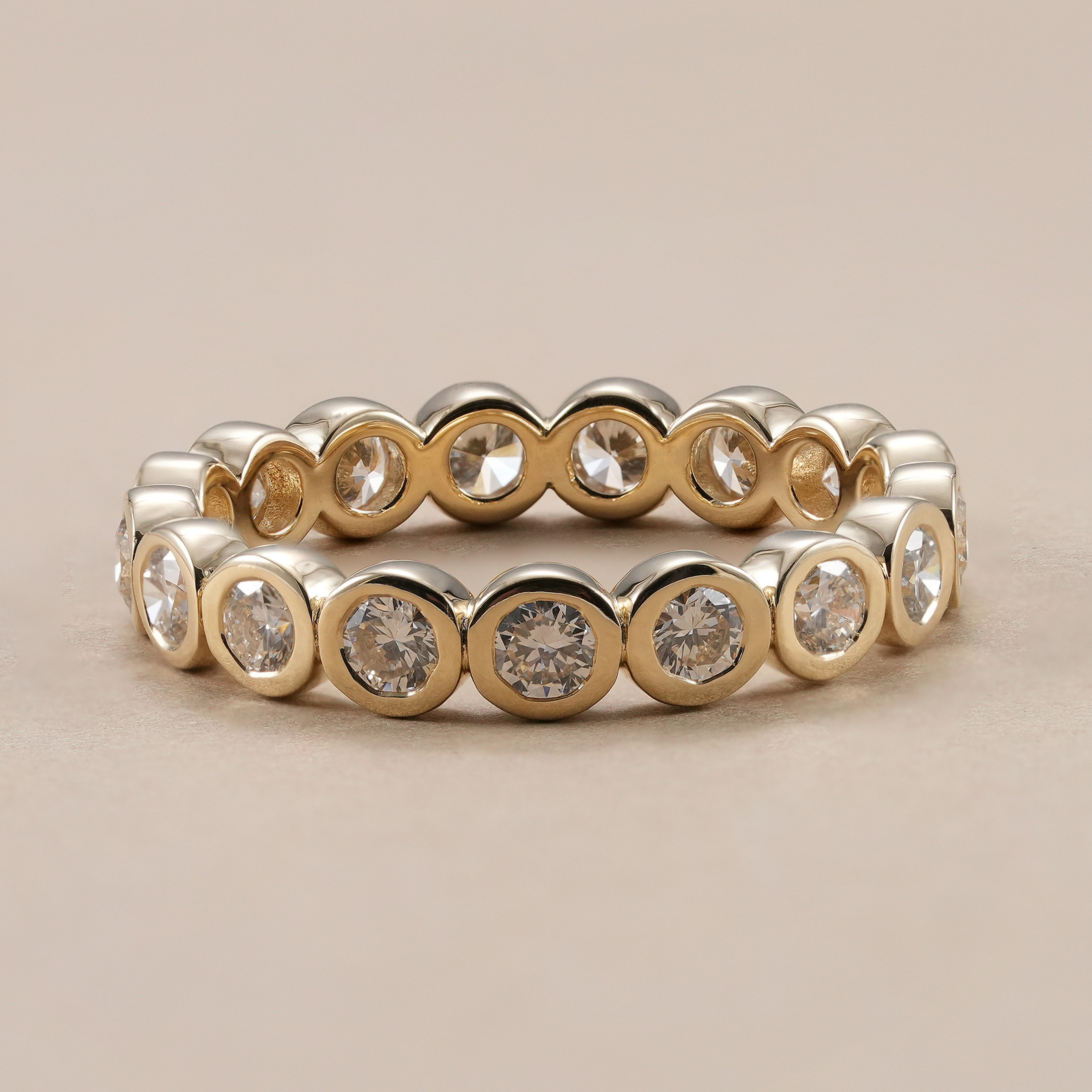 Bezel set diamond eternity ring with round lab grown diamonds in yellow gold.