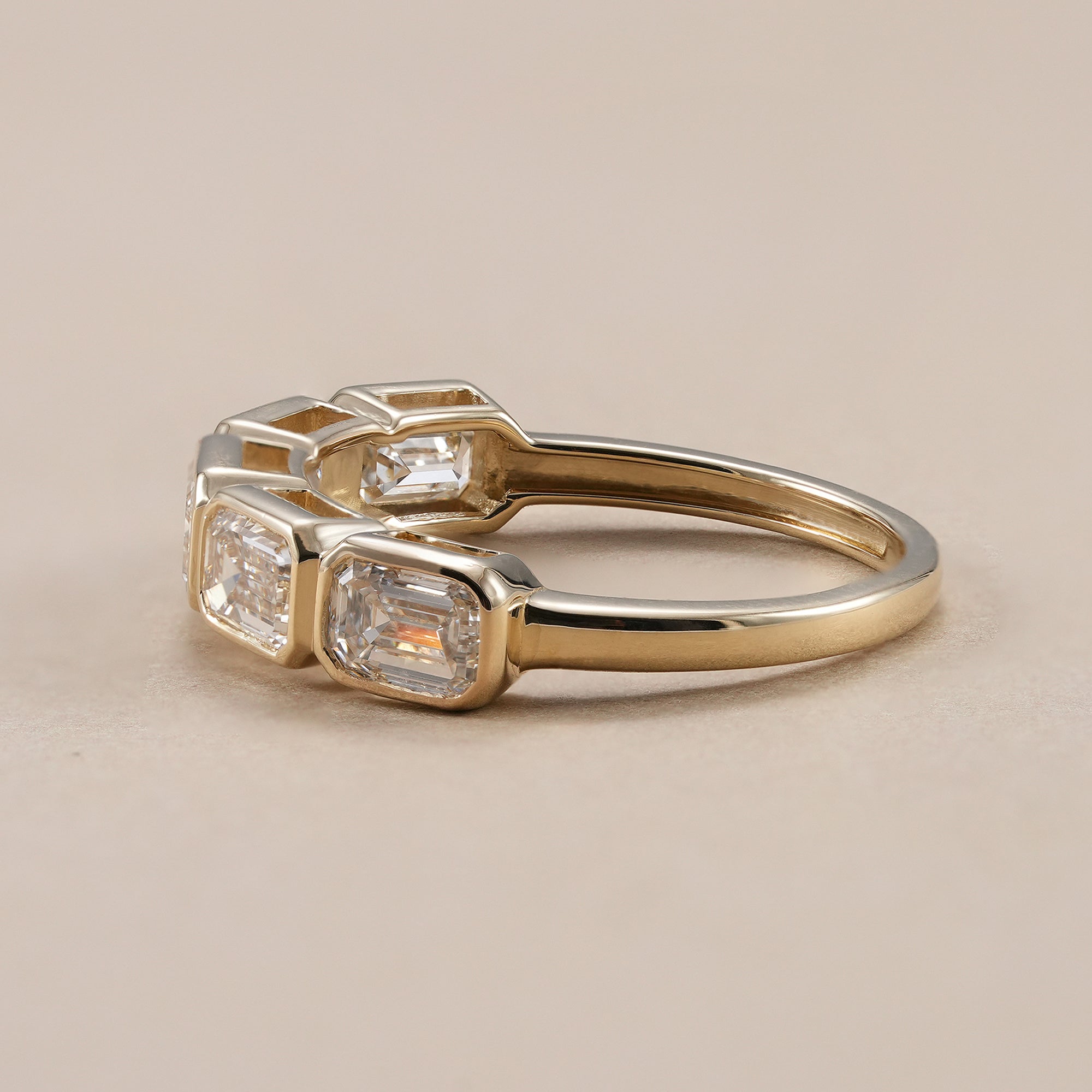 Five stone emerald diamond wedding band in yellow gold.