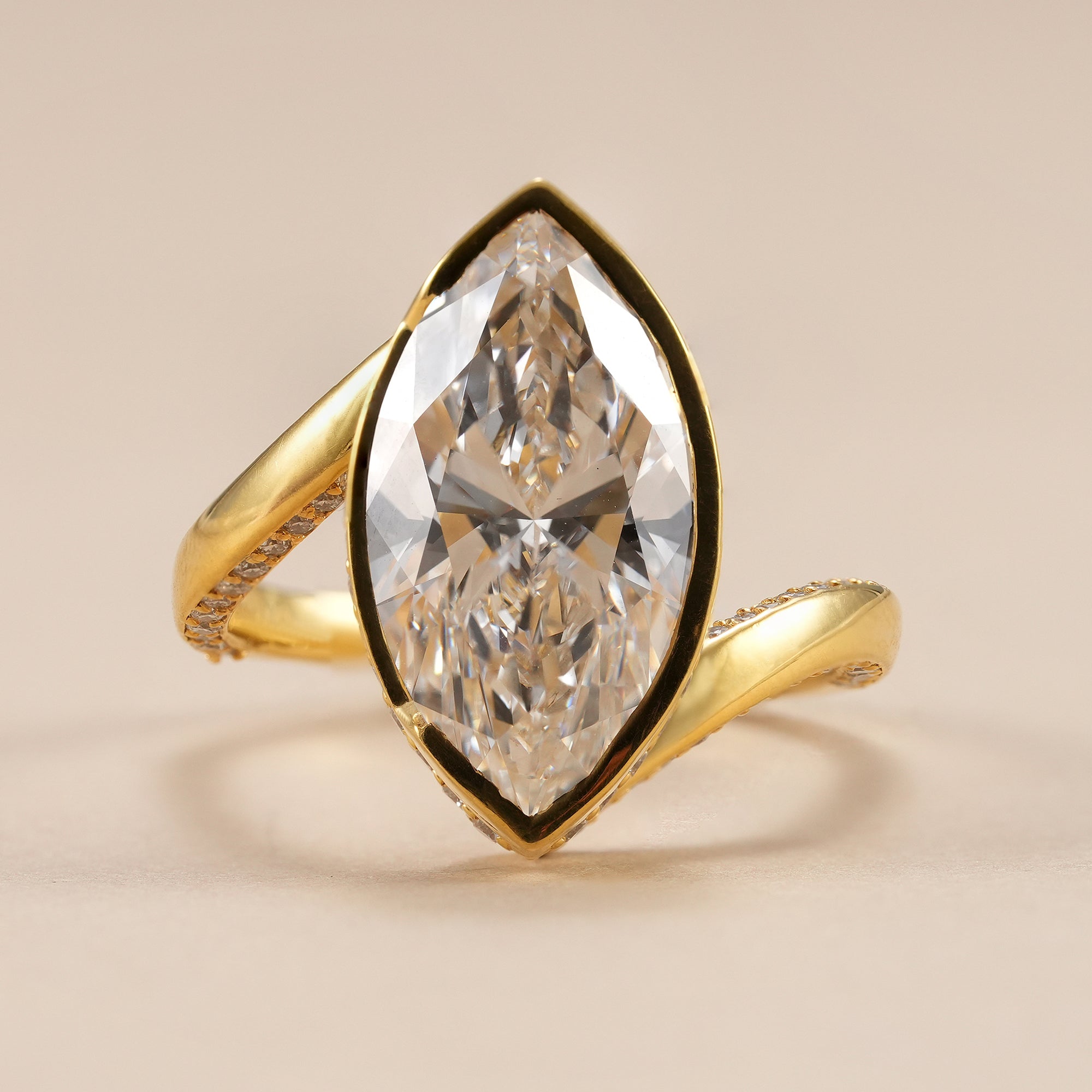 Bezel set marquise lab grown diamond engagement ring with pavé bypass band.