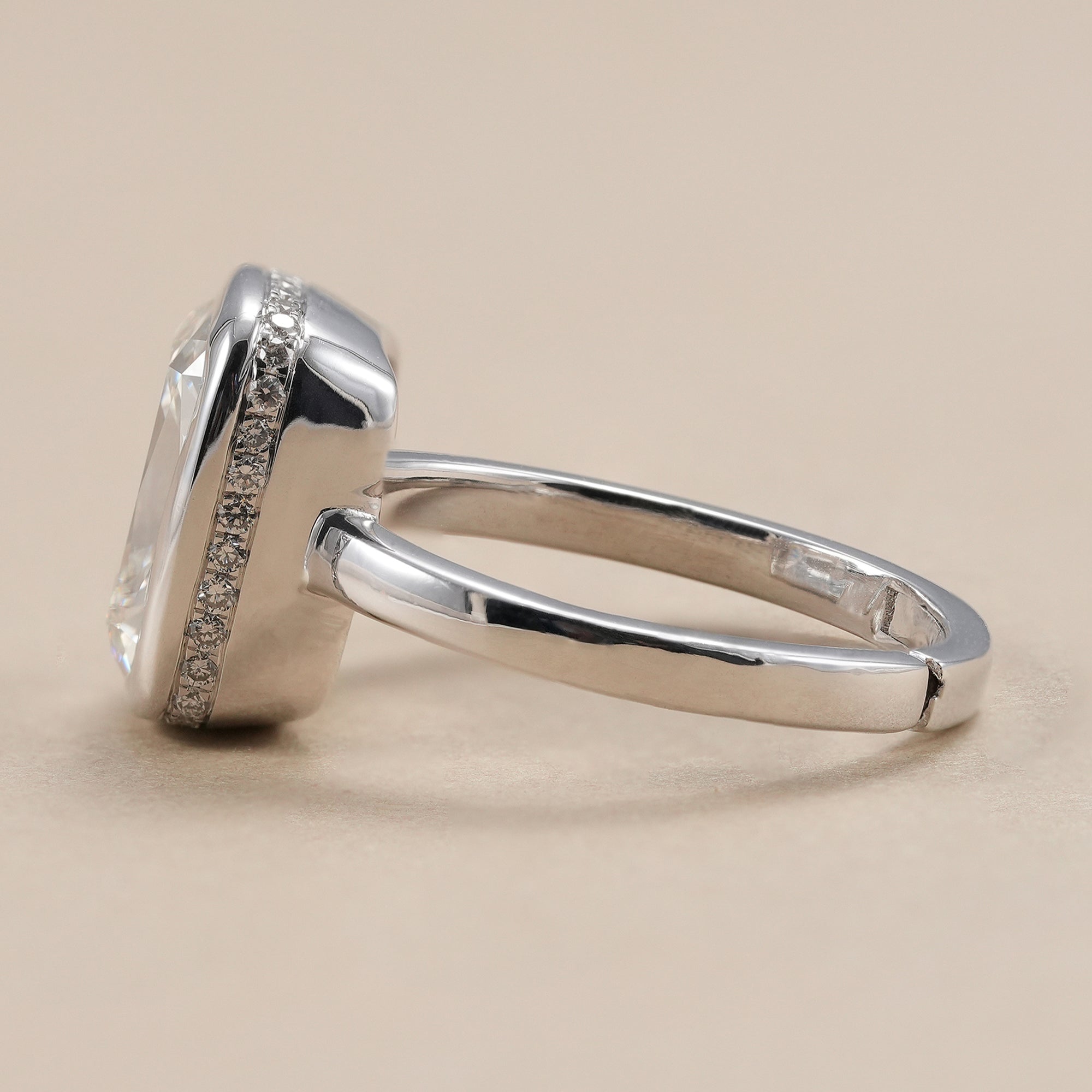 Bezel set cushion diamond solitaire ring in white gold.