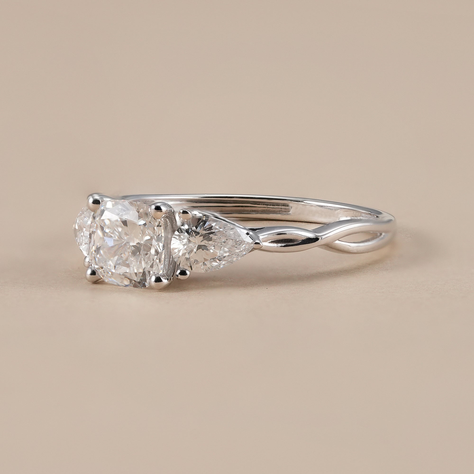 Cushion diamond ring with pear side stones in white gold