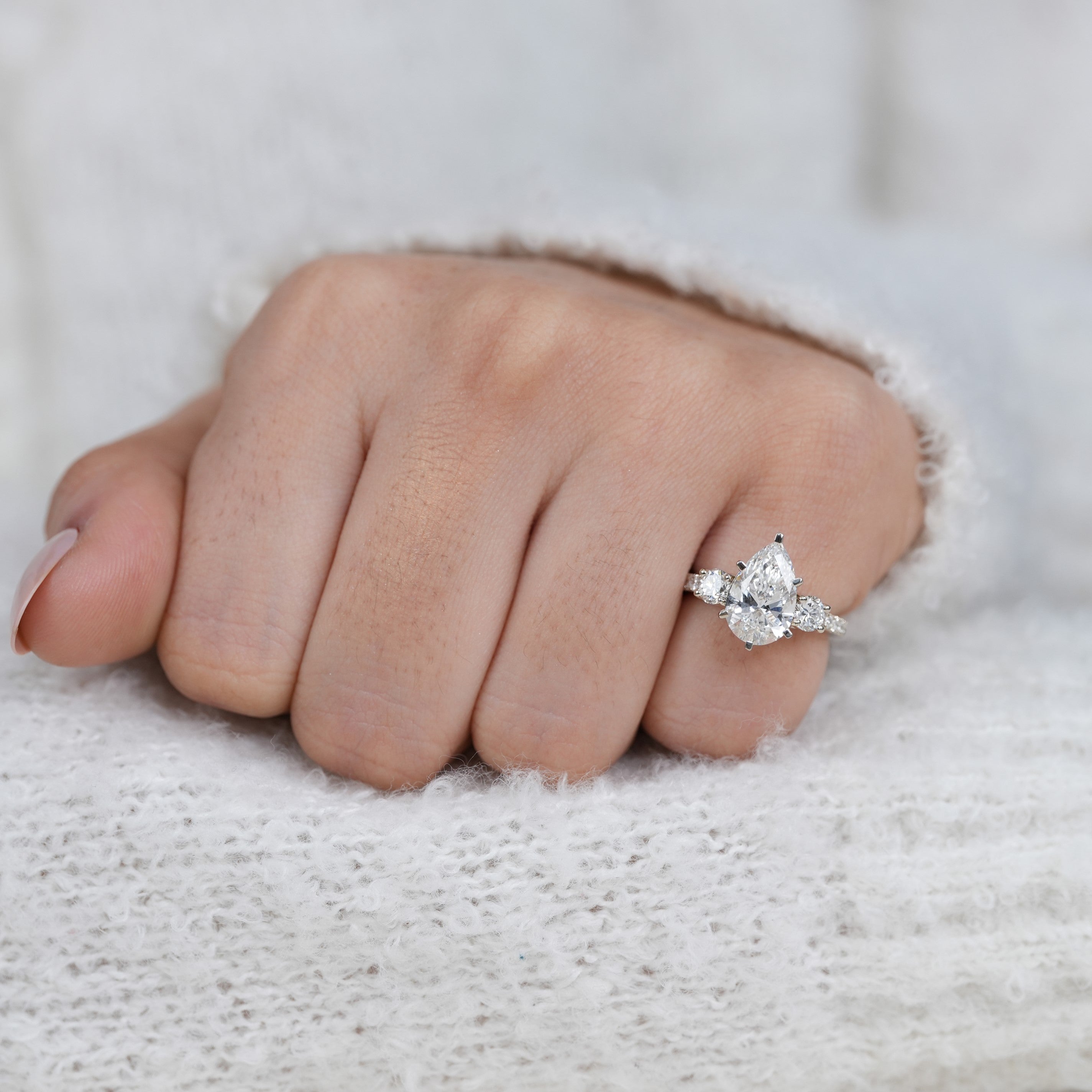 Pear shaped lab grown diamond ring with round side stones