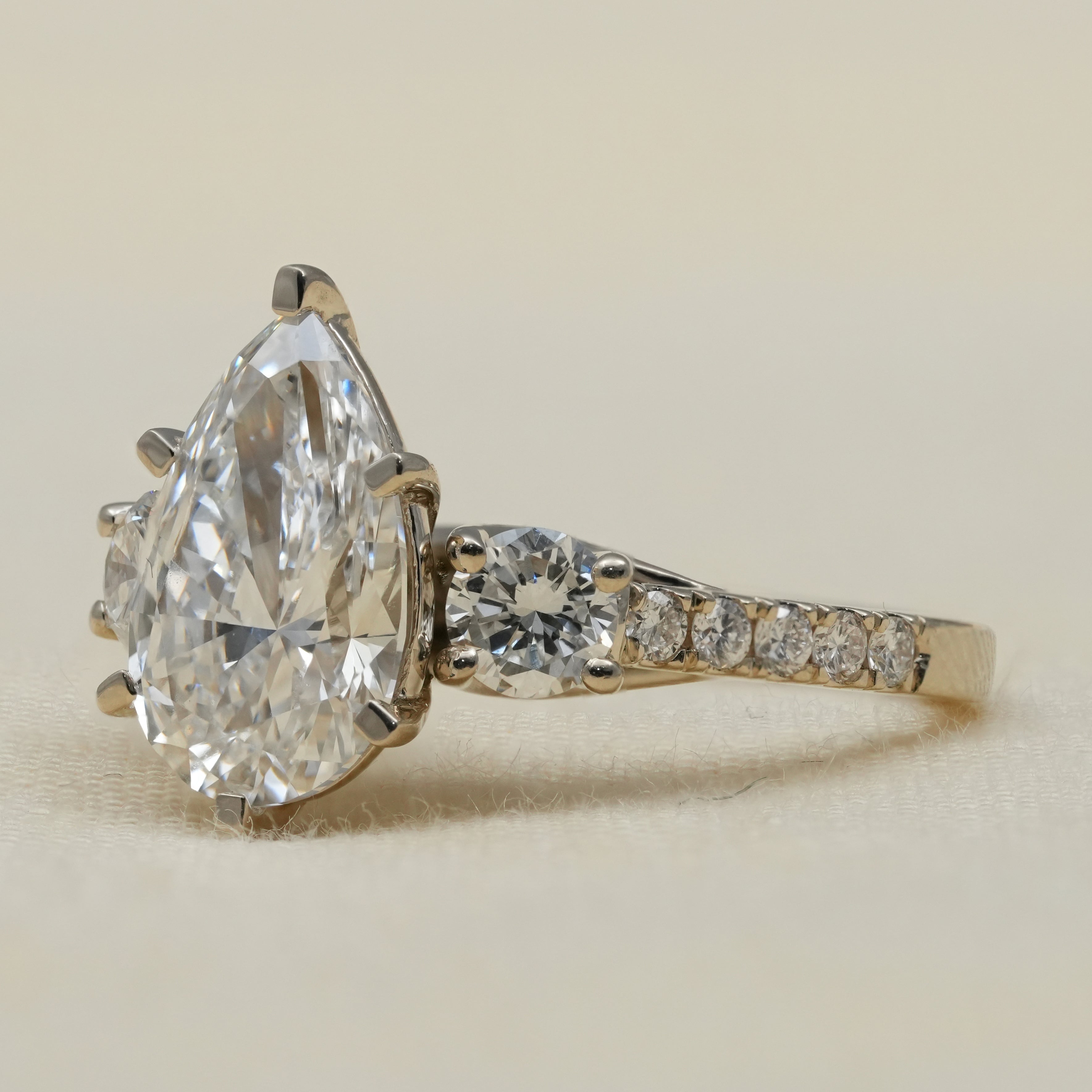 Pear cut lab grown diamond ring with round sides elegant design