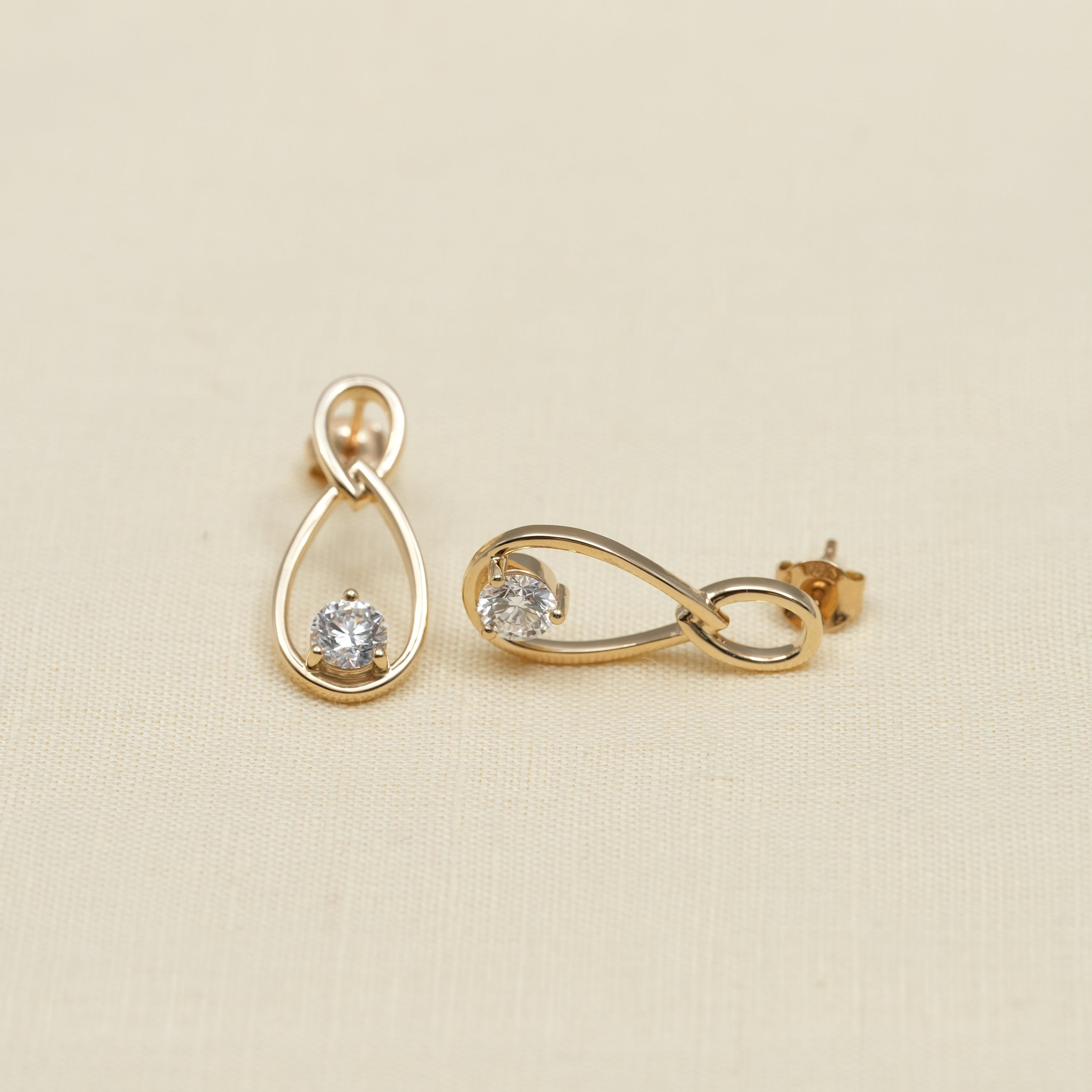Fine jewelry gold drop earrings worn on ear with diamonds