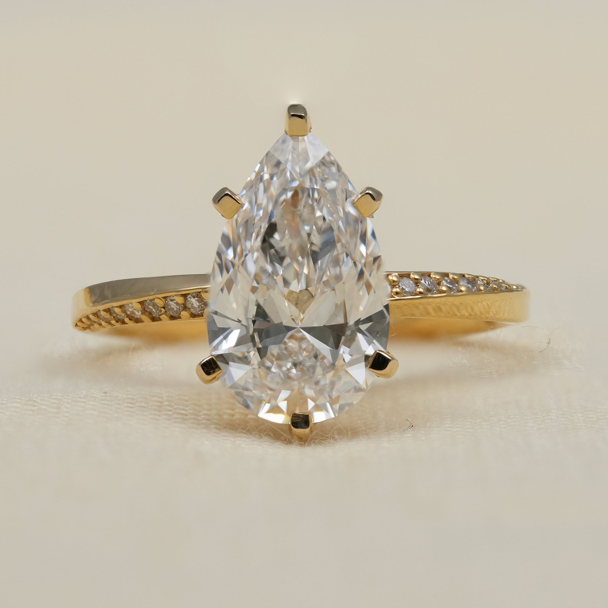 Pear cut lab grown diamond ring with yellow gold pavé band