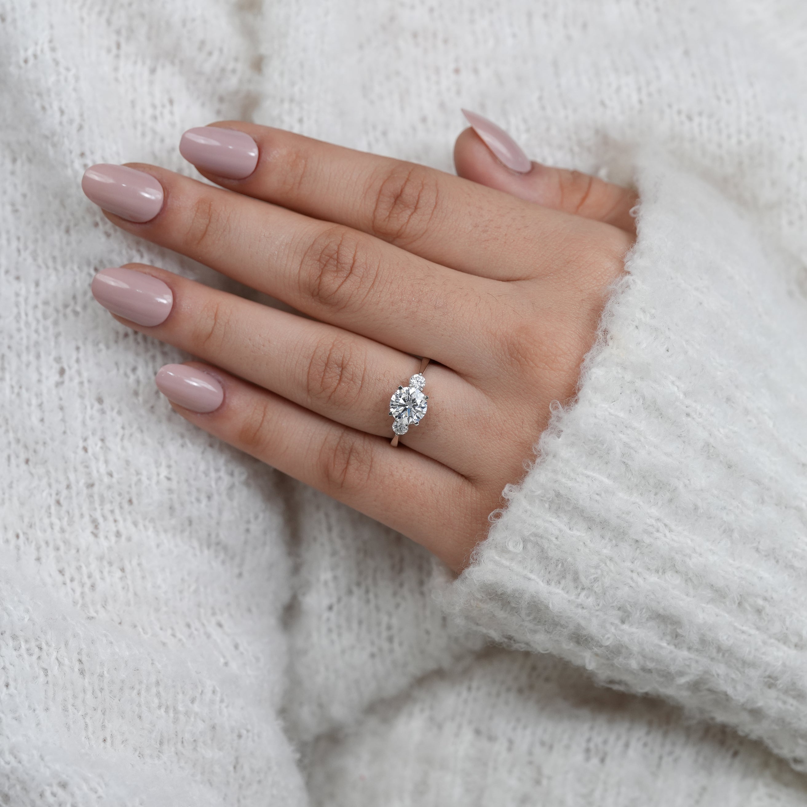 Elegant round lab grown diamond ring flanked by two side stones