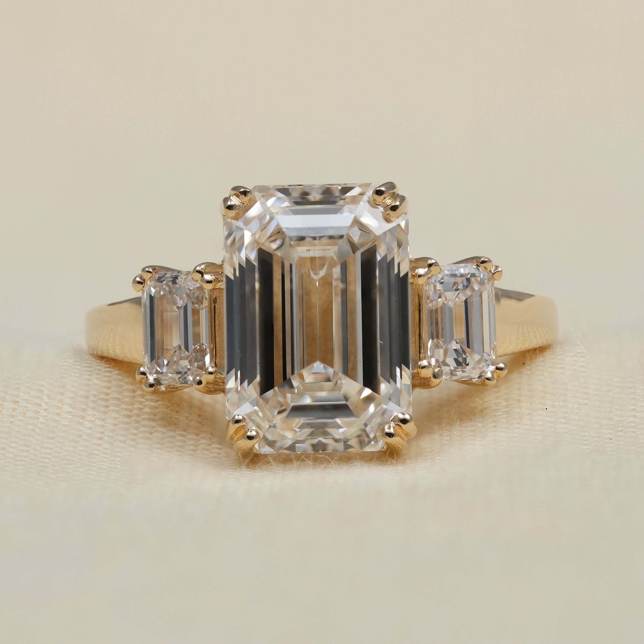 Emerald cut lab grown diamond three stone engagement ring yellow gold
