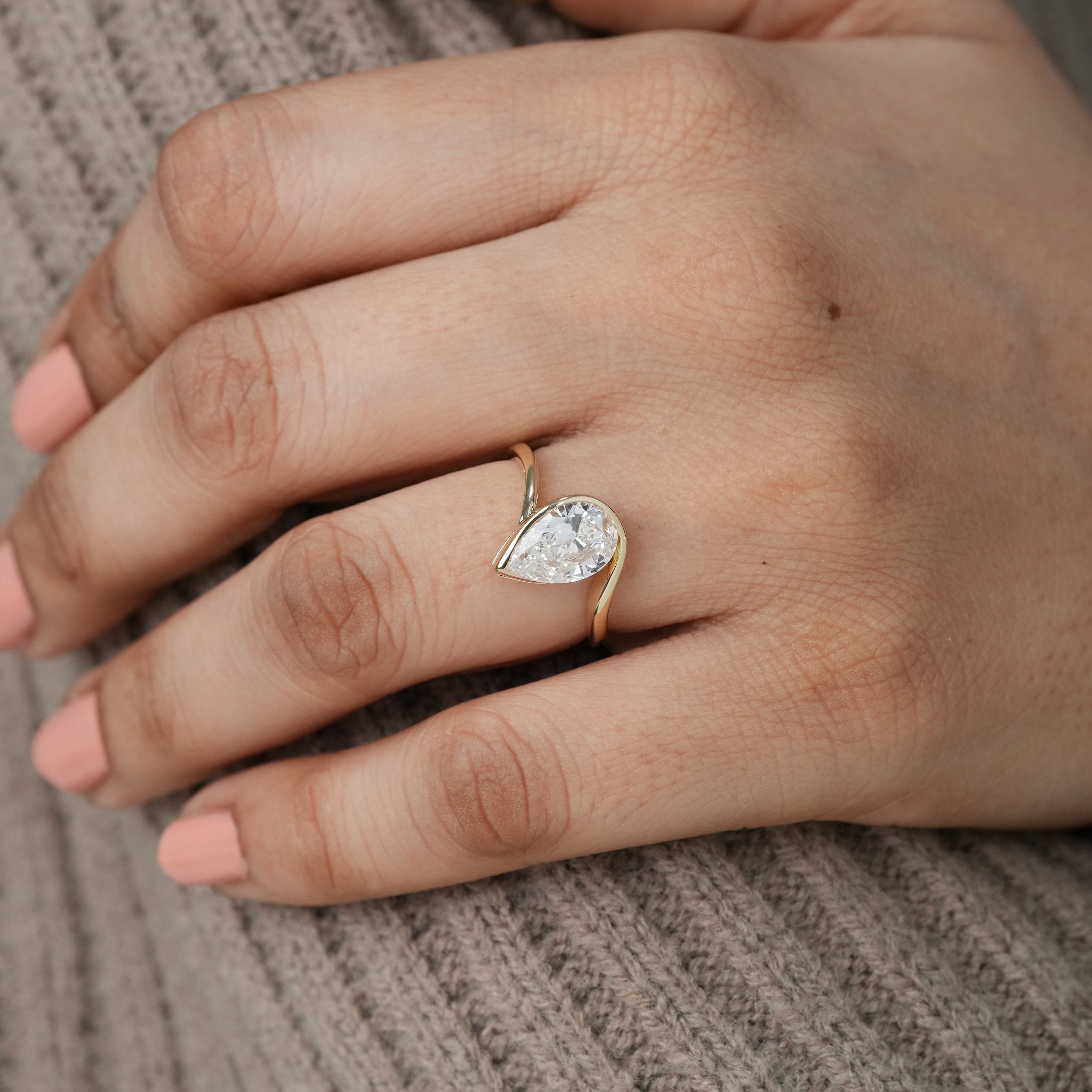 Elegant curved gold band cradling pear lab grown diamond solitaire