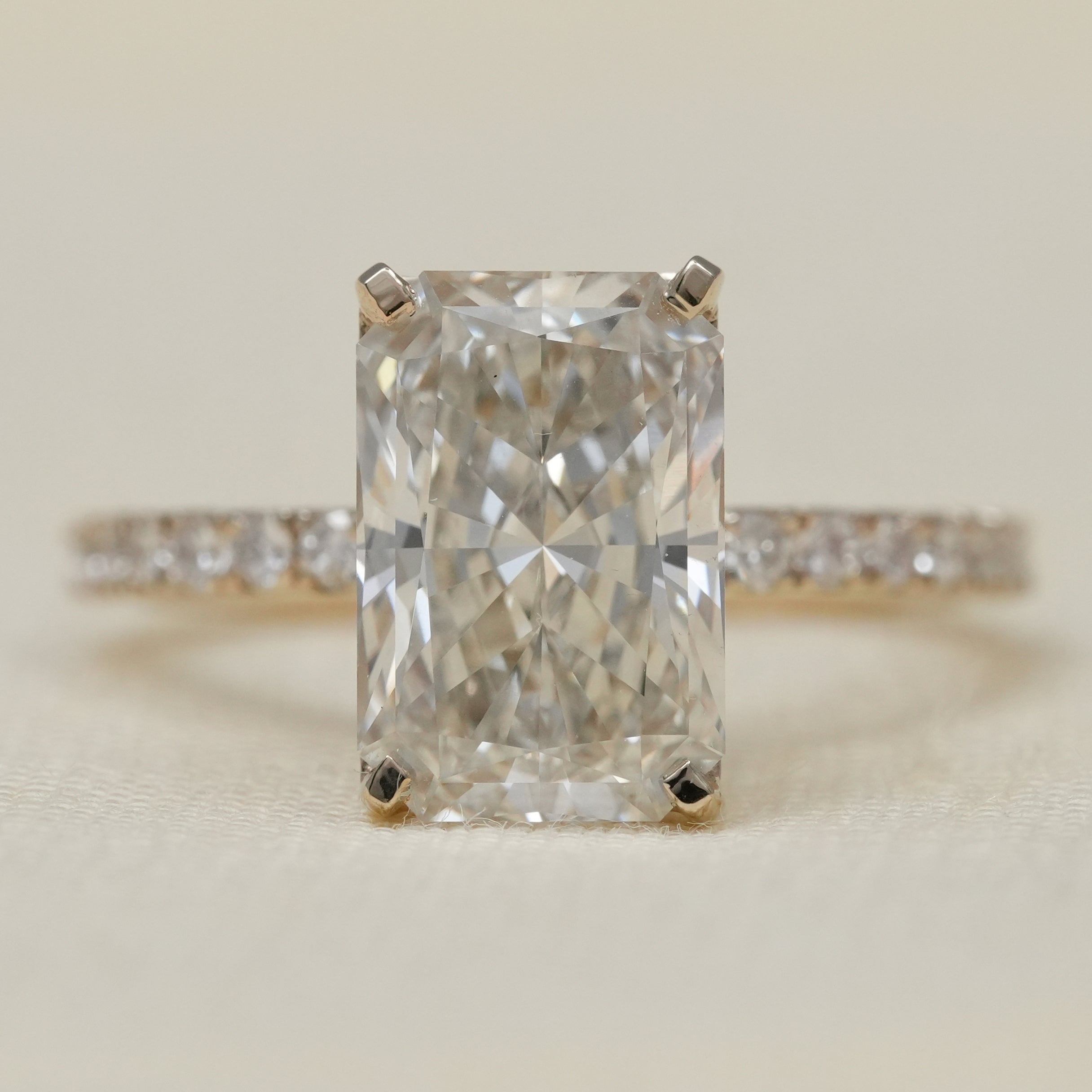 Radiant cut lab-grown diamond engagement ring with pavé gold band.
