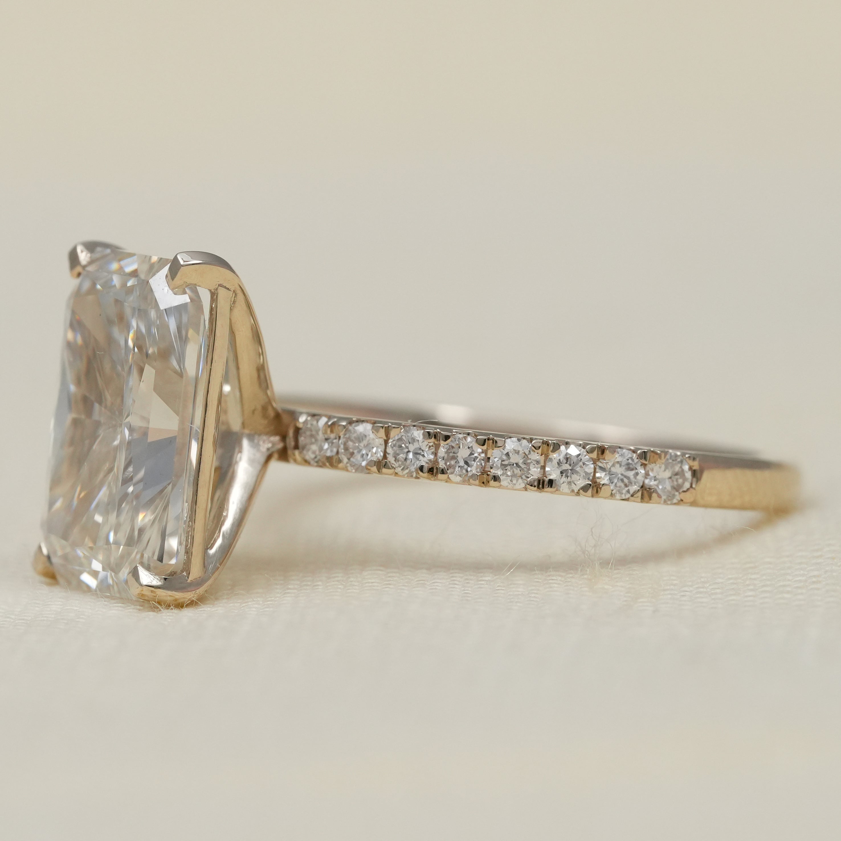 Elegant lab grown diamond radiant solitaire ring slim pavé yellow gold band.