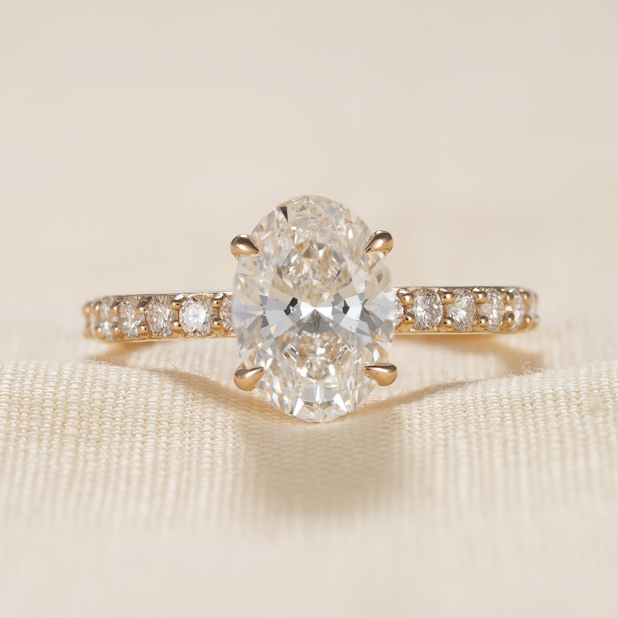 Oval hidden halo diamond engagement ring with pavé yellow gold band