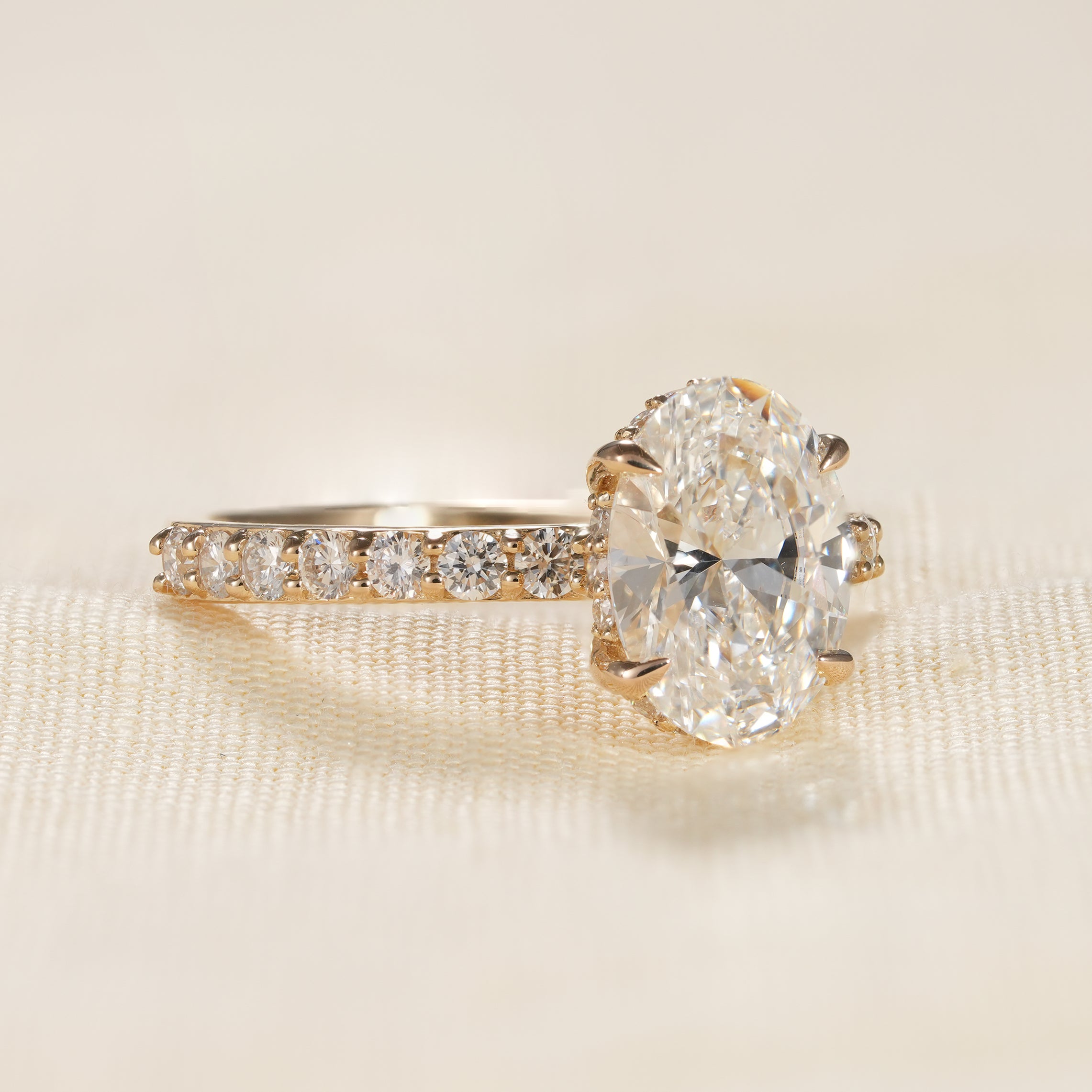 Oval solitaire engagement ring with pavé diamond band and hidden halo