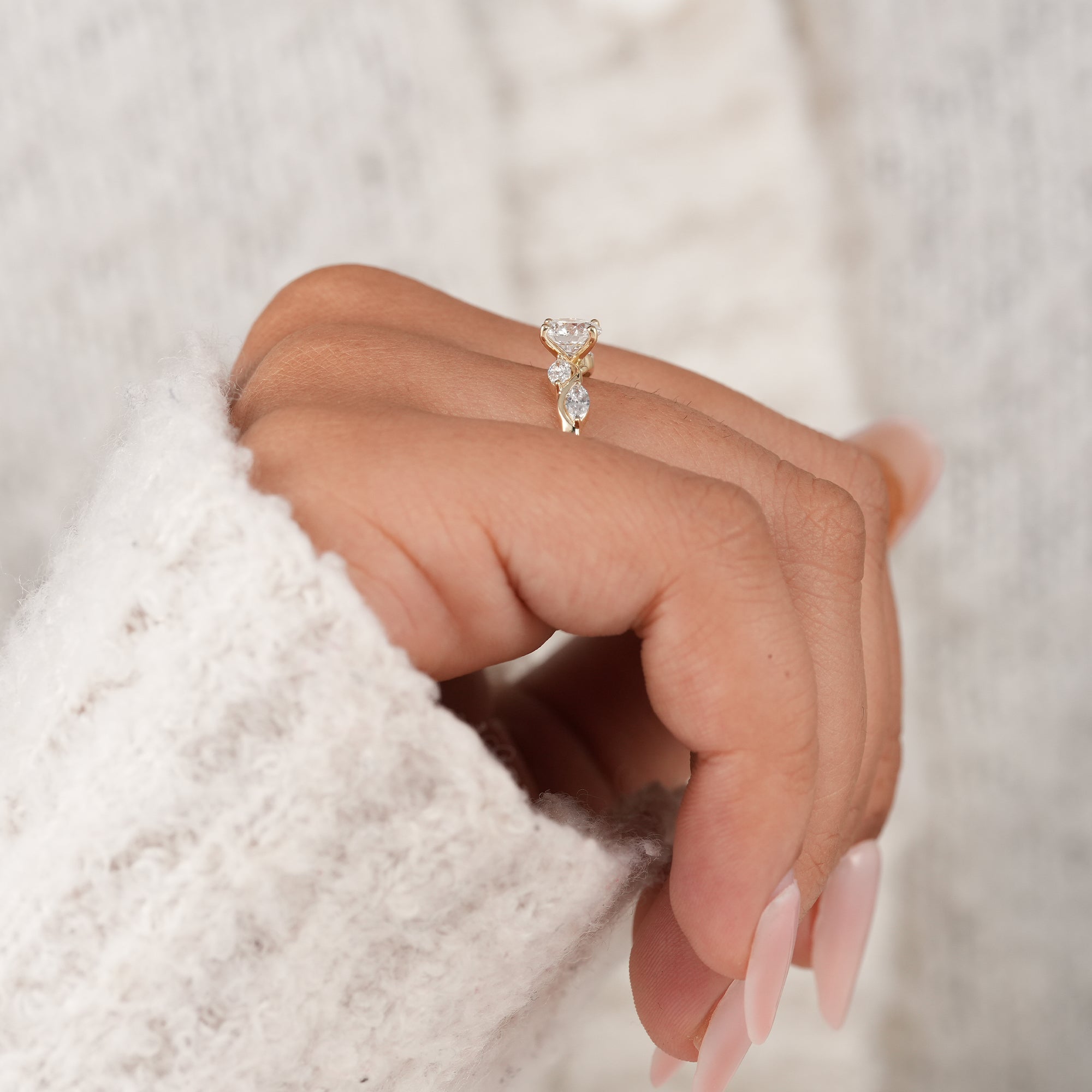 Round brilliant cut diamond ring with marquise diamond wave design.