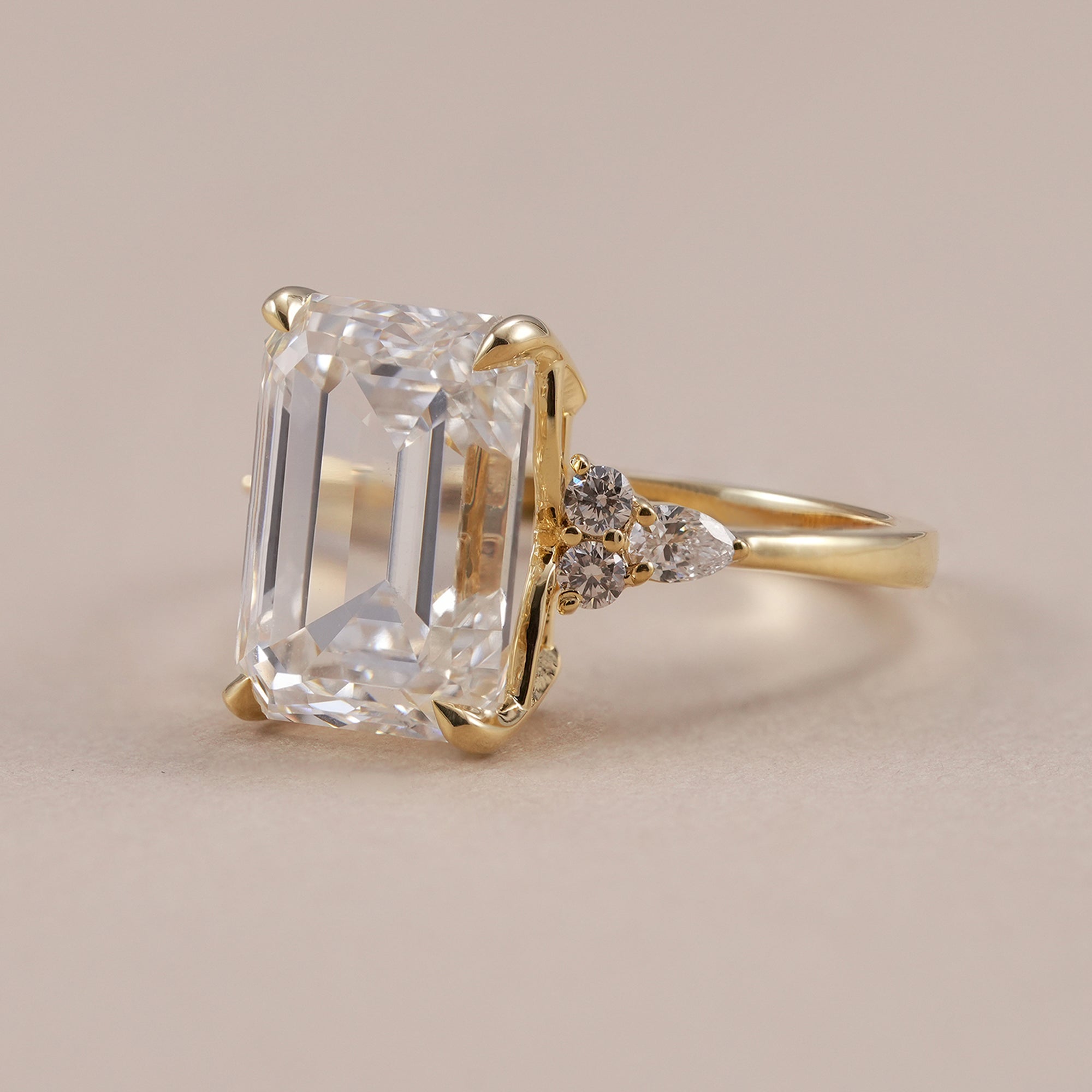 Emerald diamond engagement ring with pear and round side stones