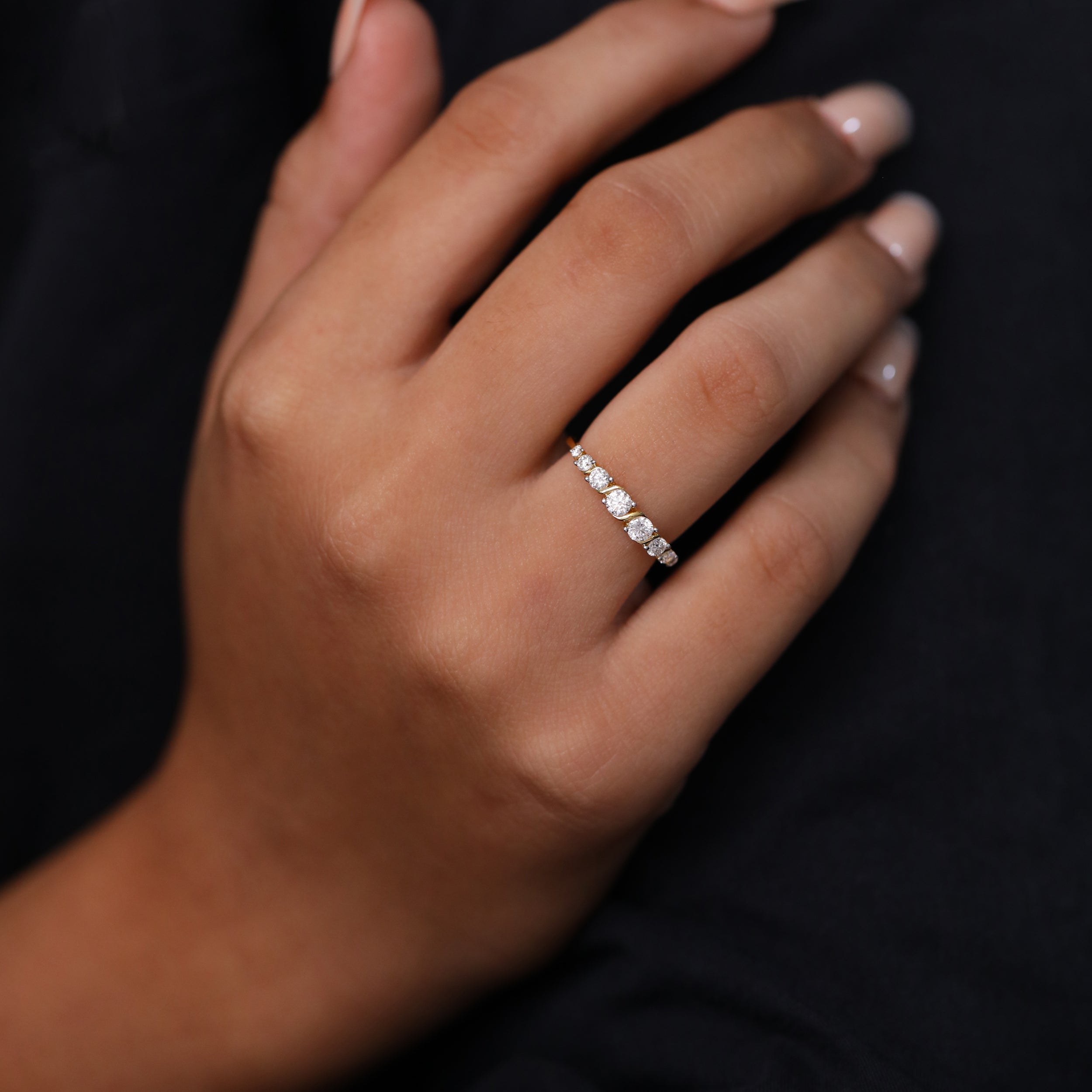 Fine yellow gold ring with perfectly aligned round diamonds, designed in a modern curved diamond band style.