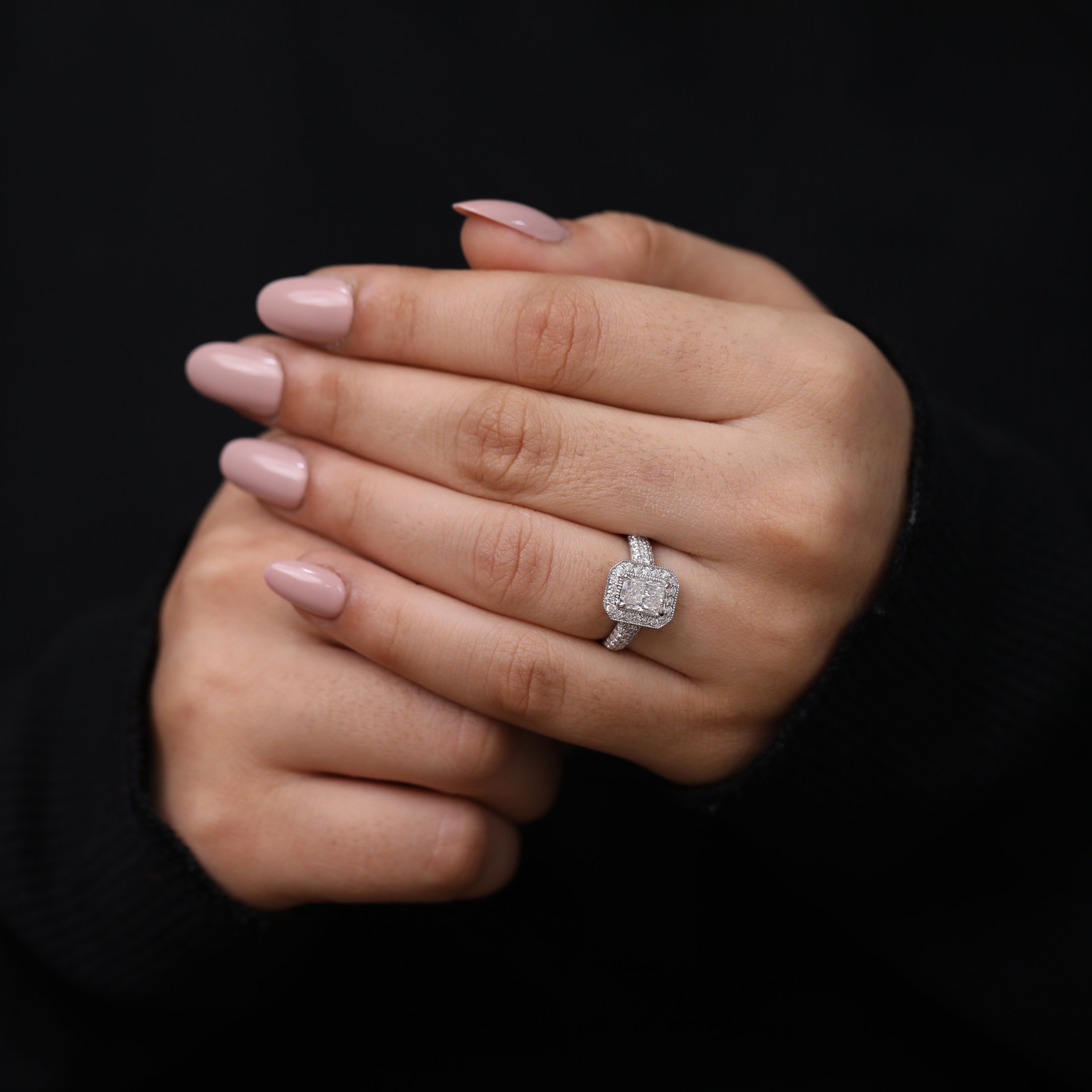 Modern engagement ring with an emerald cut lab diamond and halo frame.