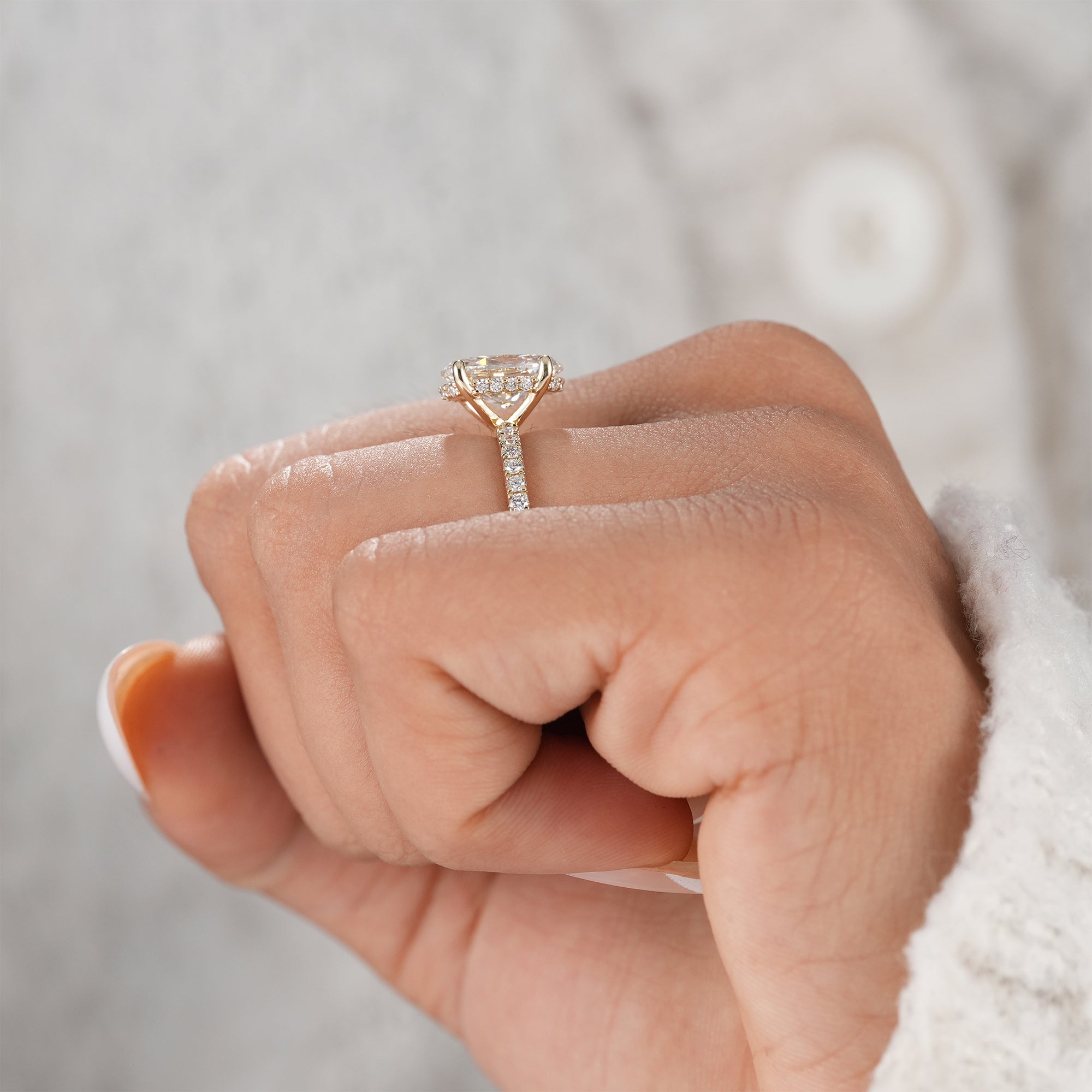 Classic oval diamond engagement ring with pavé shank.