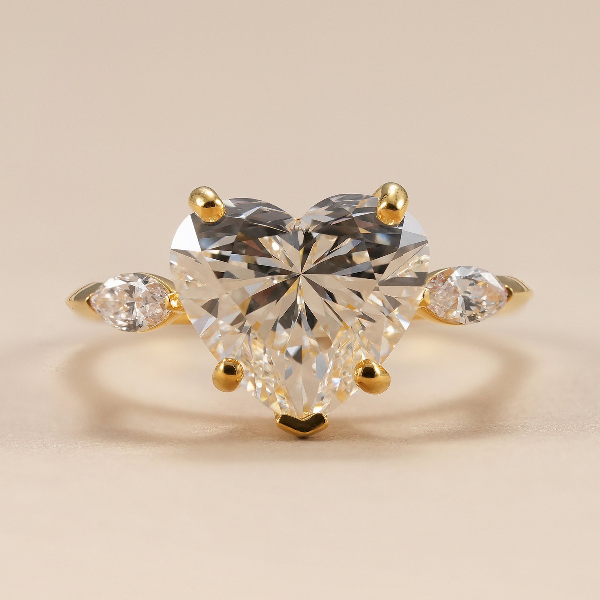 Heart shaped lab grown diamond ring with pear side diamonds in yellow gold.