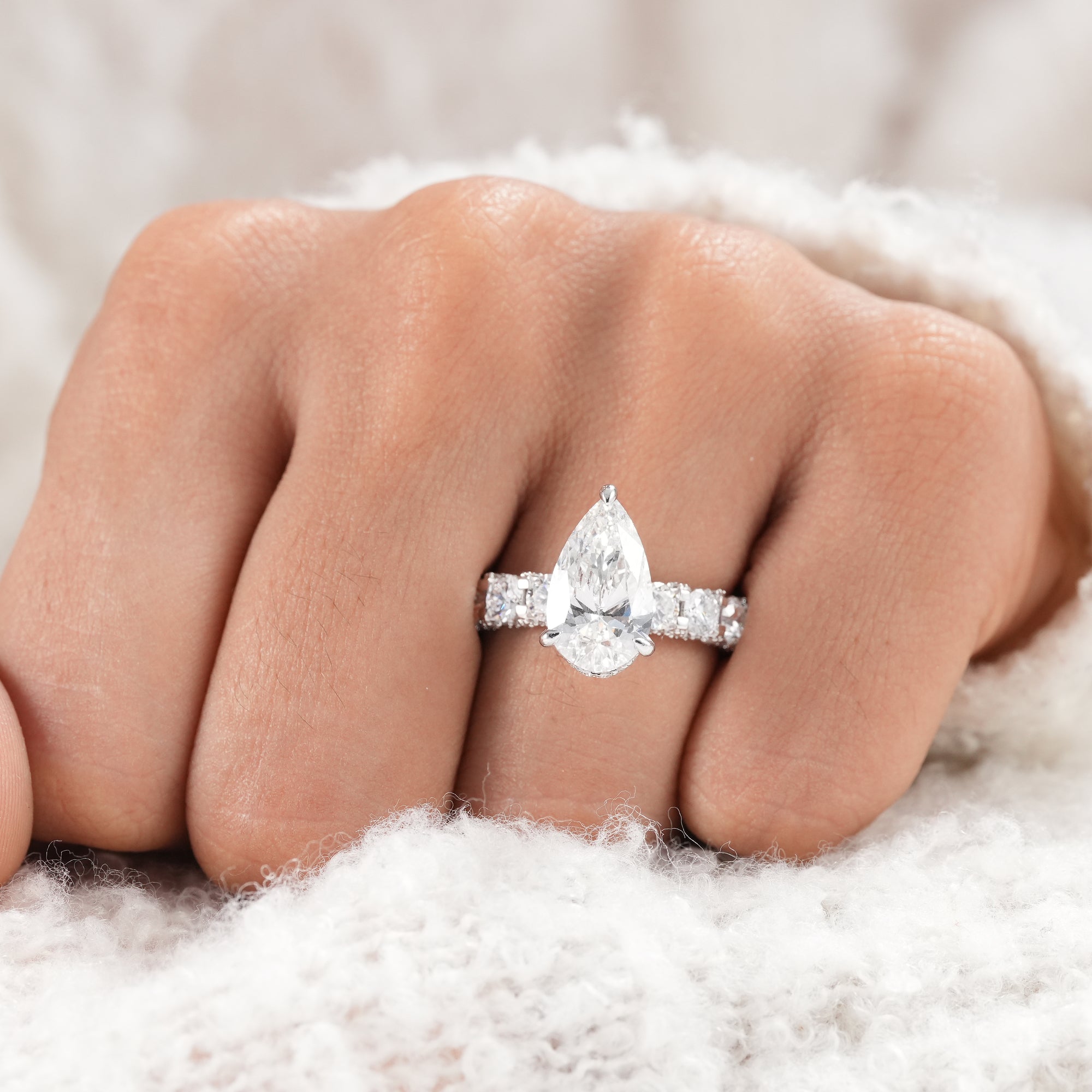 Hidden halo pear diamond ring with four prong setting.