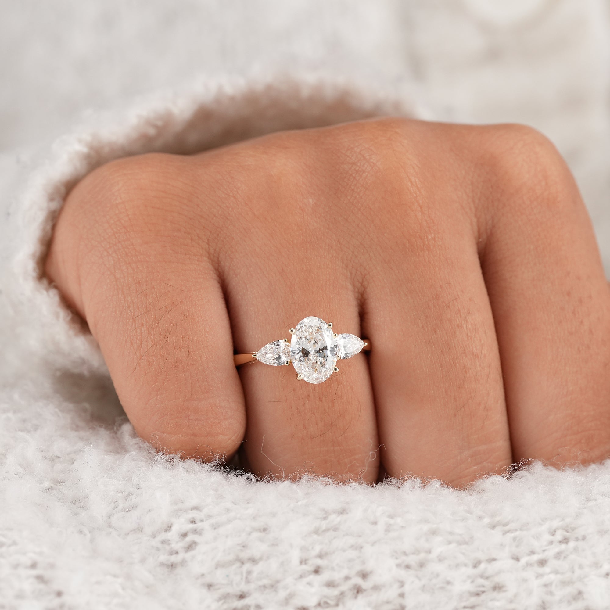 Three stone oval engagement ring on finger