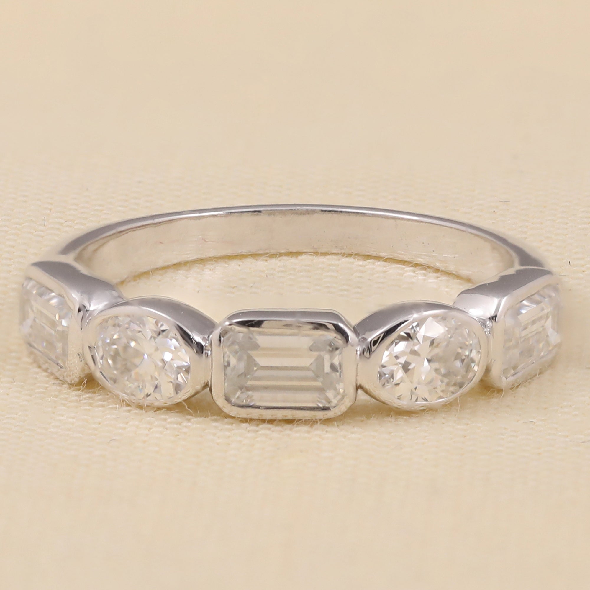 Five-stone lab diamond ring featuring emerald, oval, and round-cut stones in a modern band design