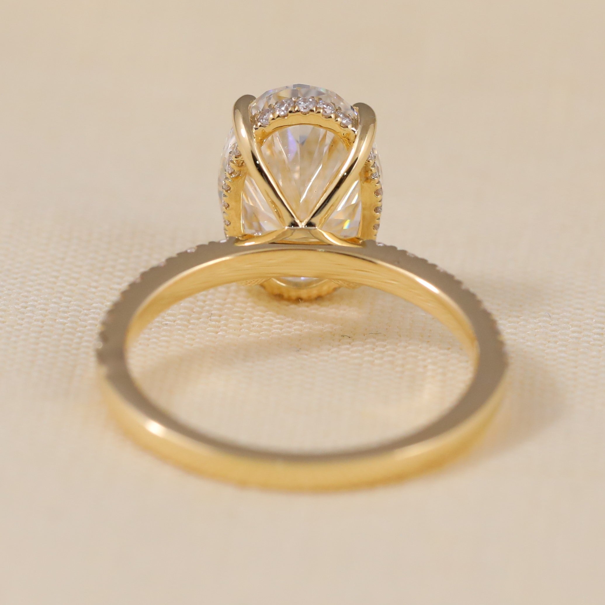 Oval diamond-style ring with a gold band and pavé accents.