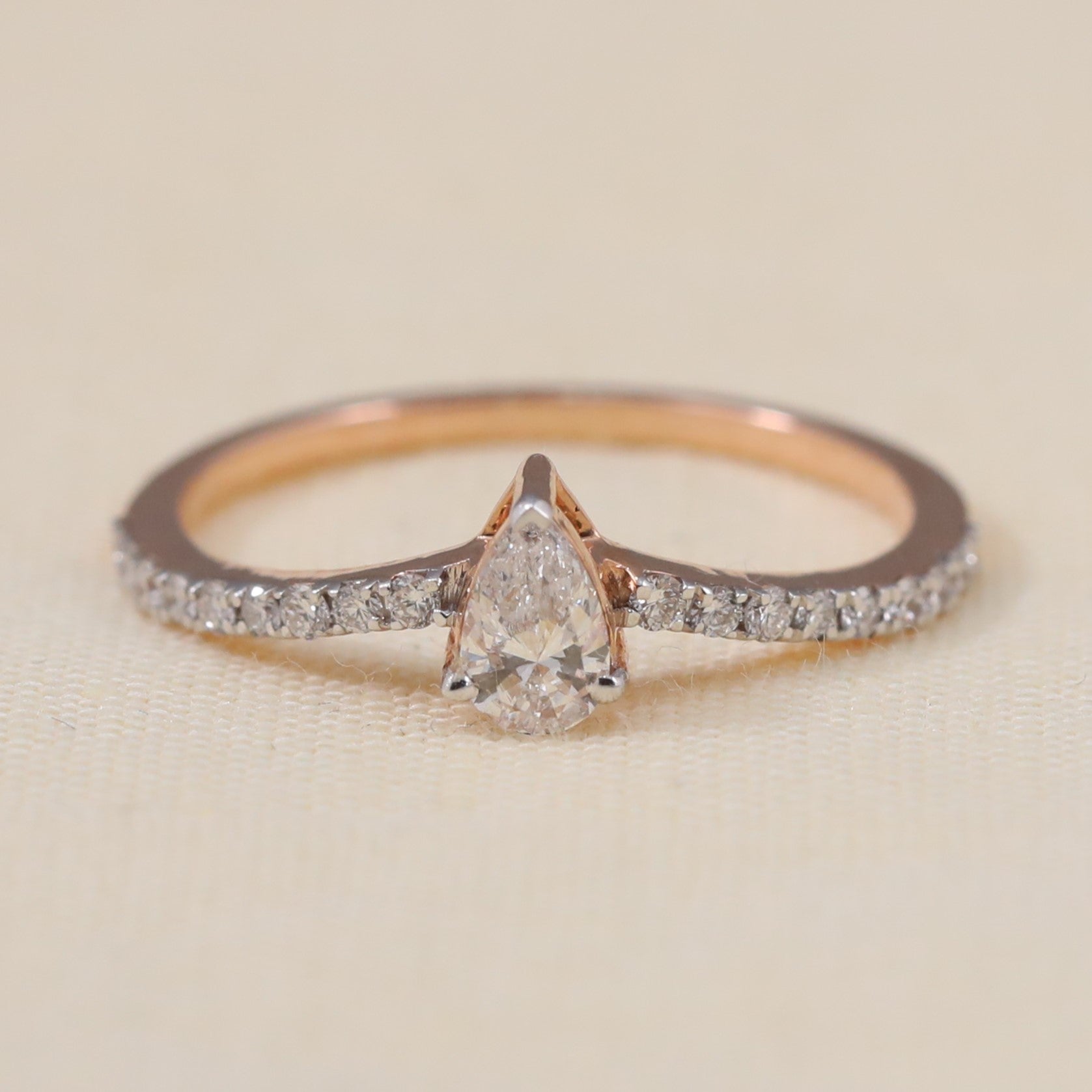 Pear shaped lab grown diamond engagement ring featuring a delicate pavé band