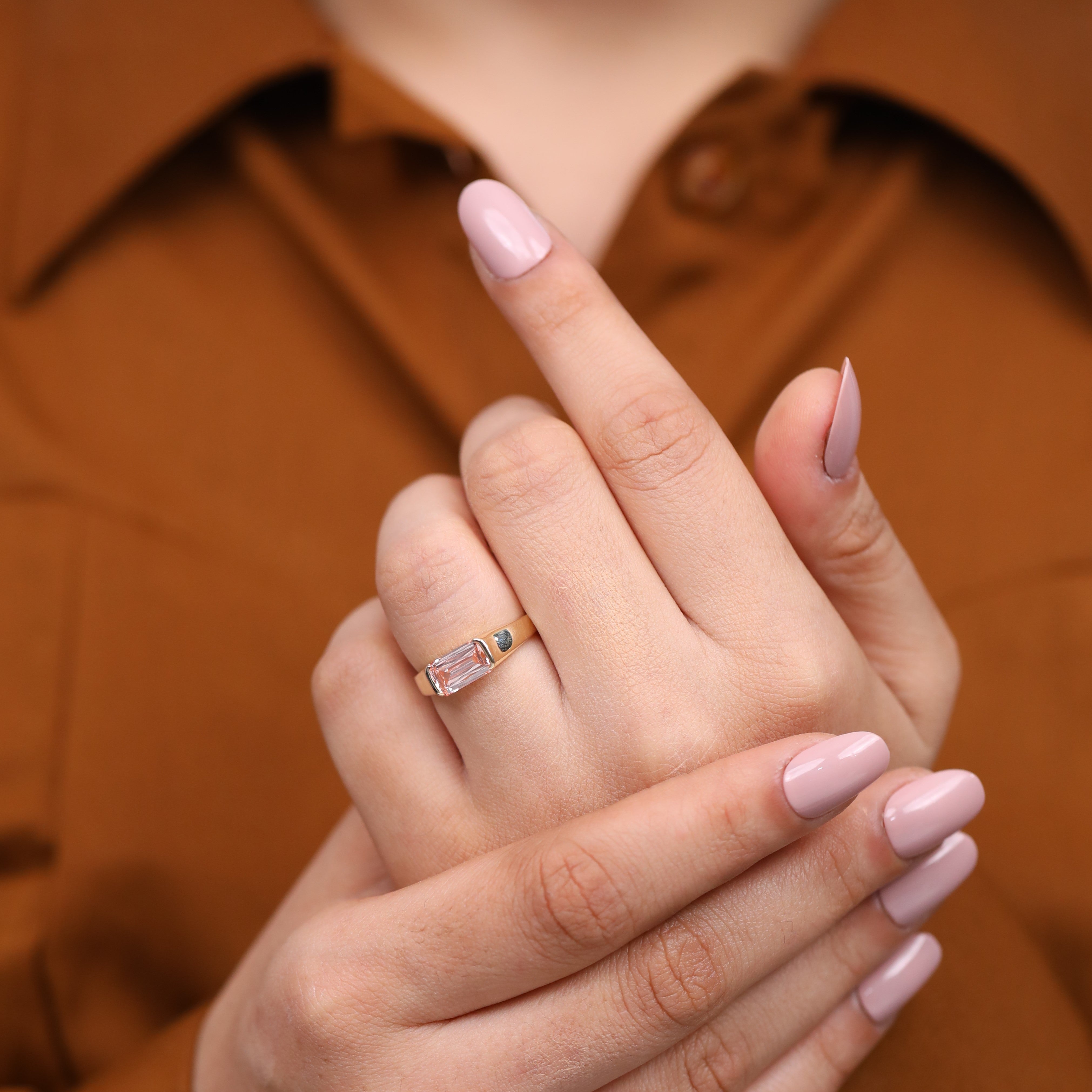 Gold statement ring featuring bezel set emerald cut pink lab grown diamond.