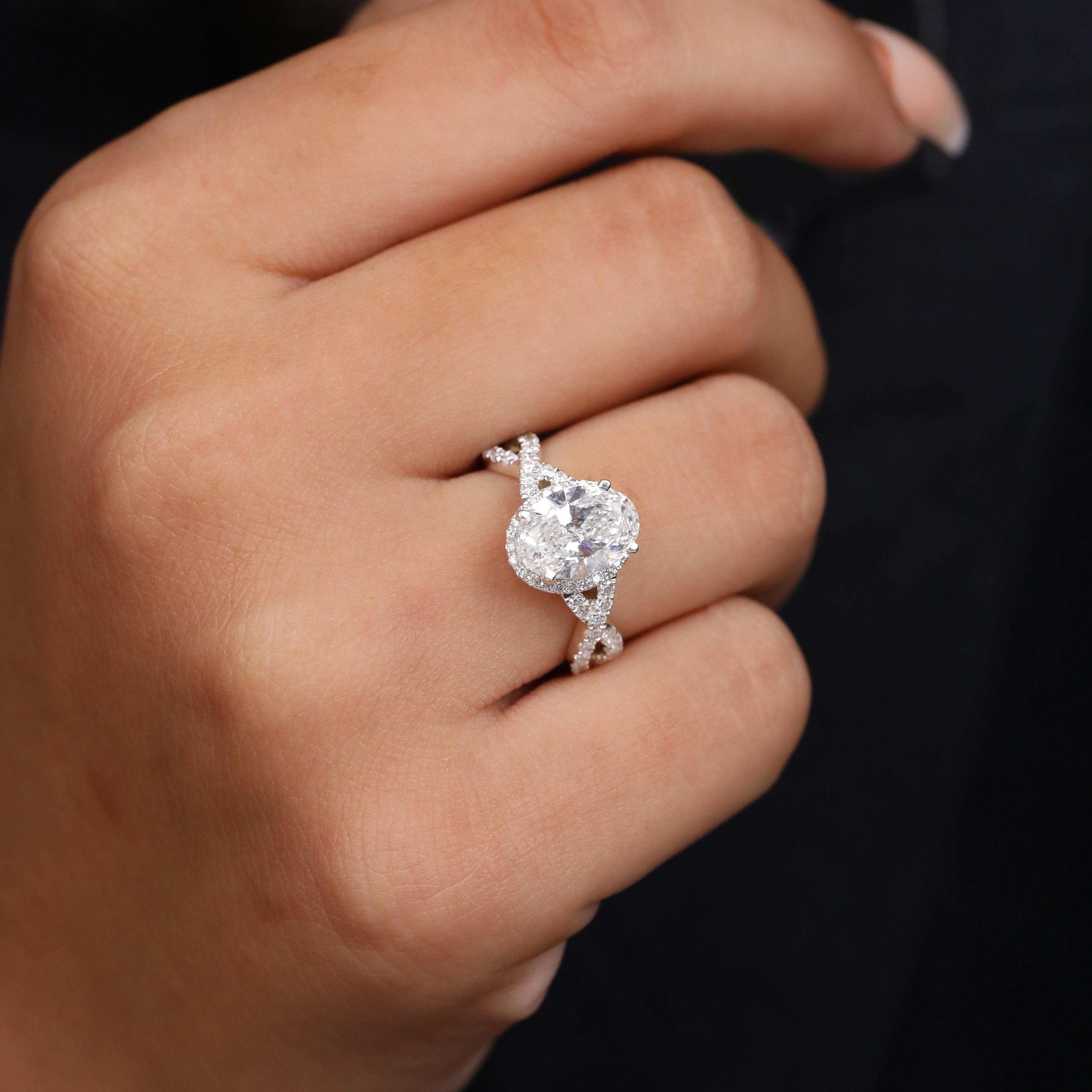 Oval diamond engagement ring set in white gold with a halo and woven pavé band.