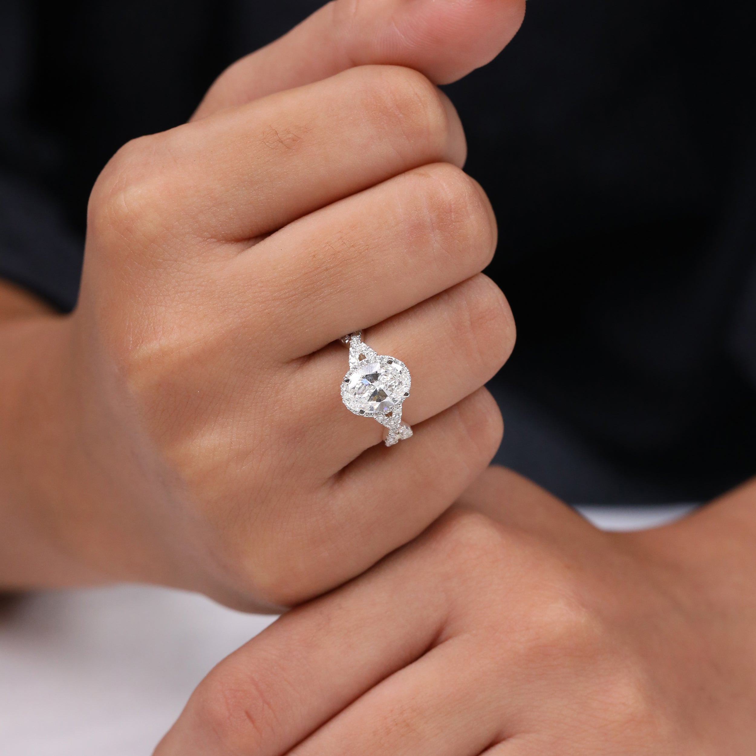 Oval center diamond engagement ring with intricate crisscross pavé band