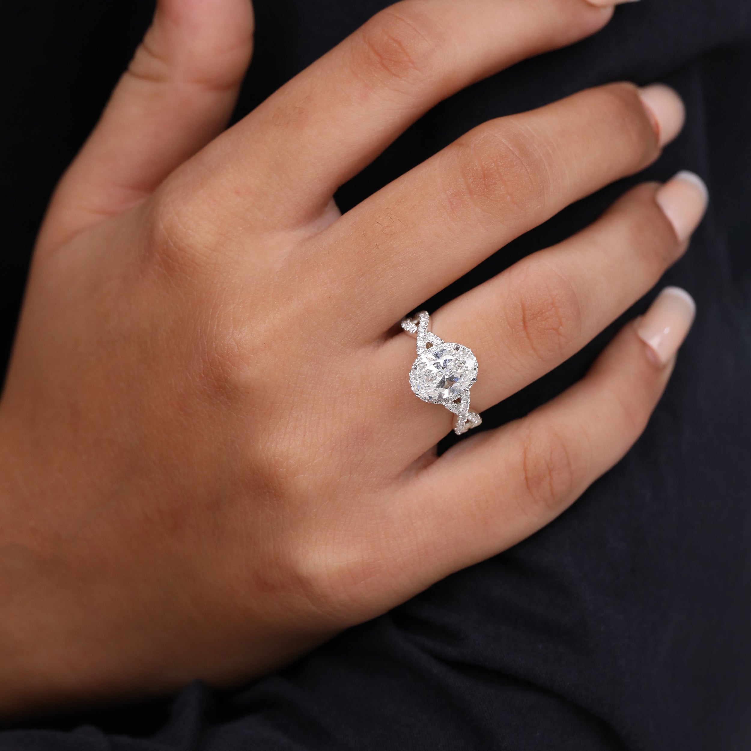 Oval halo ring featuring a brilliant center diamond and an intertwined shank.