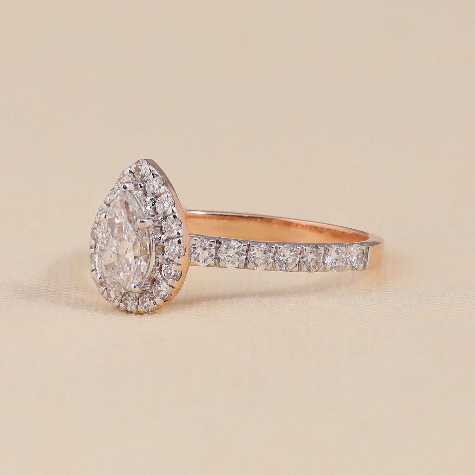 Rose gold engagement ring featuring a pear shaped lab grown diamond and halo accents