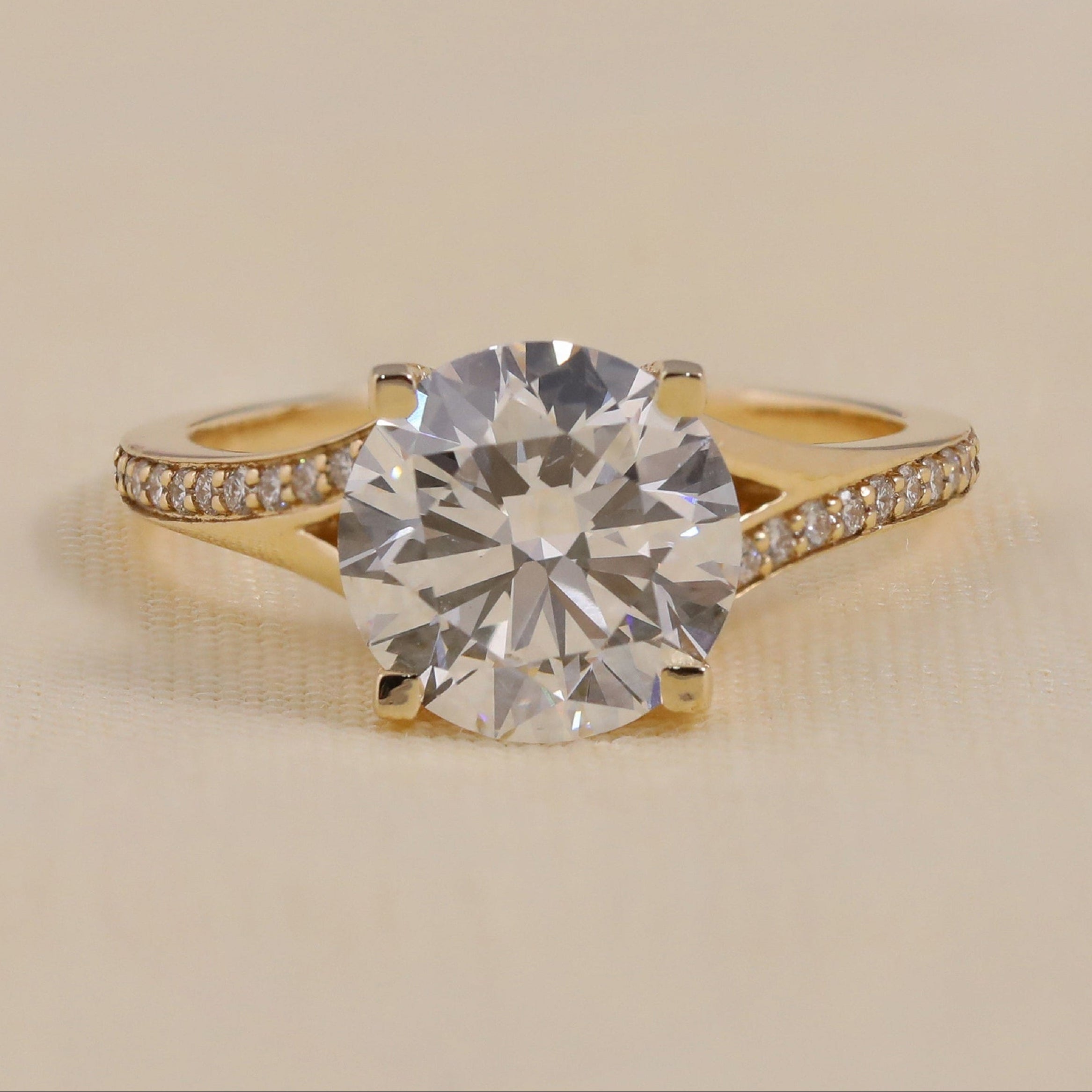 Round-cut diamond engagement ring in yellow gold with pavé band
