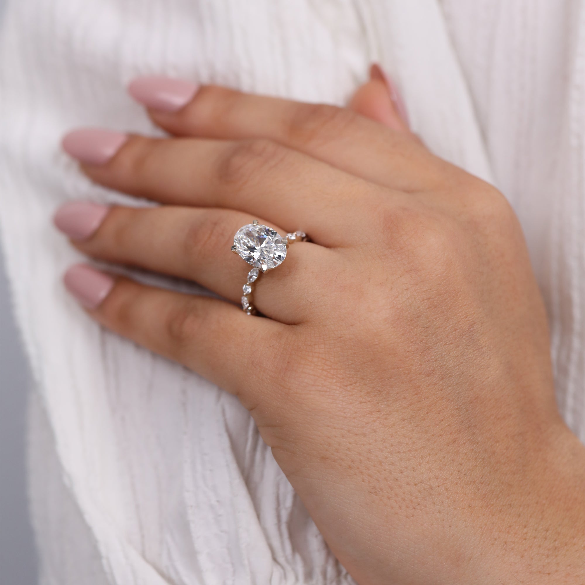 Oval cut lab grown diamond engagement ring with marquise and round side stones in white gold