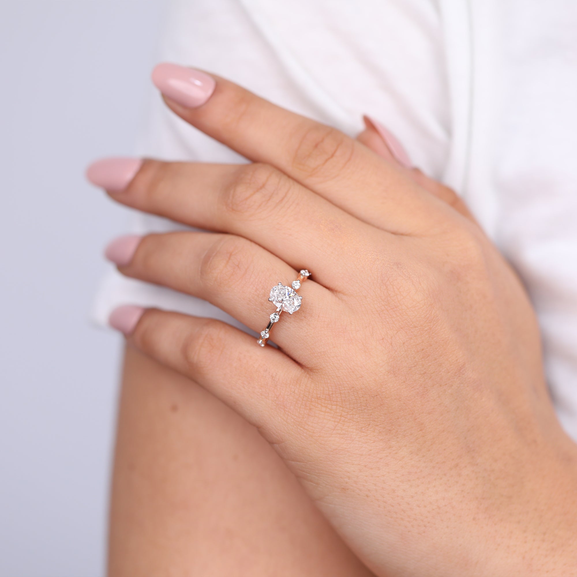 Oval lab grown diamond engagement ring in rose gold with unique side stone arrangement