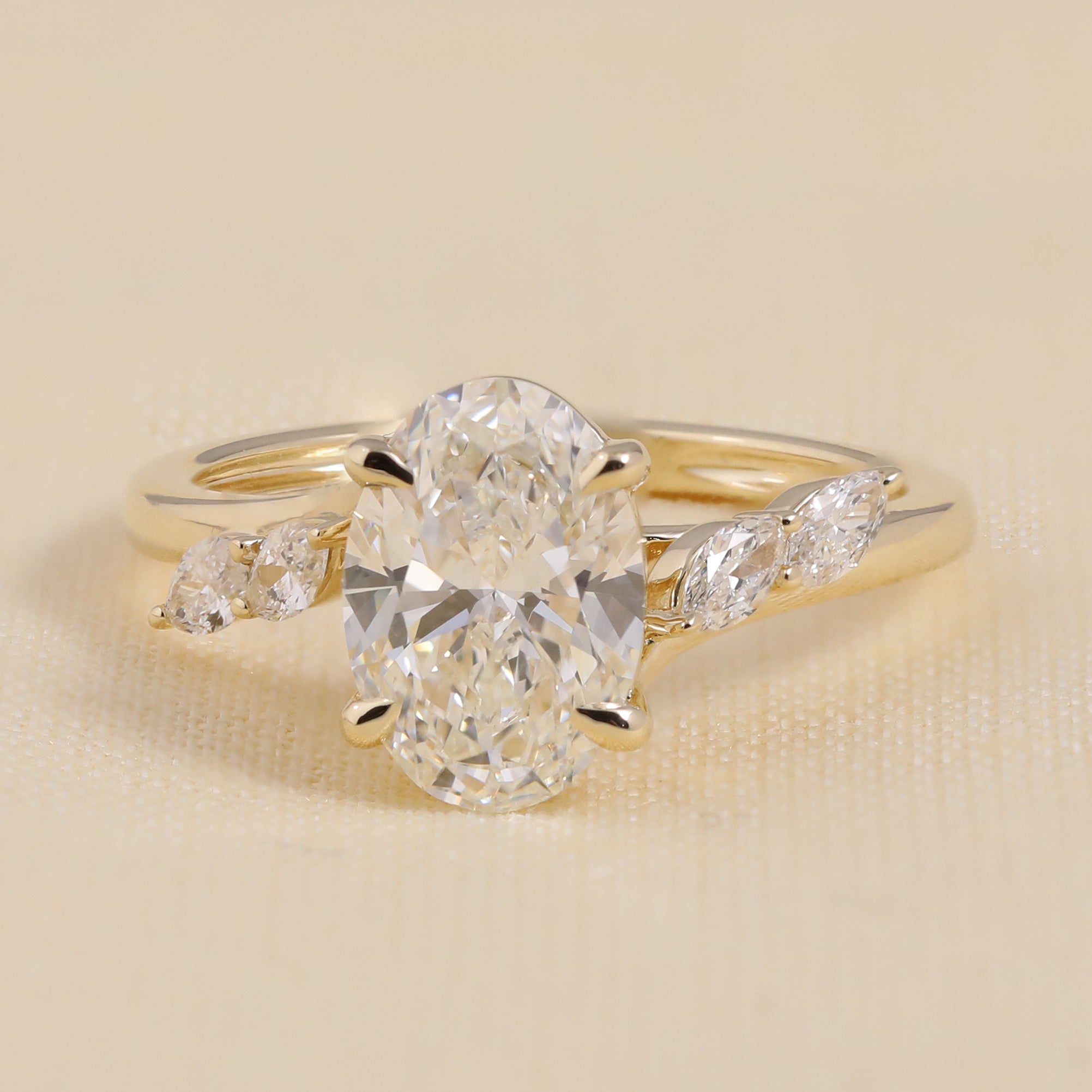 Oval-cut diamond engagement ring in yellow gold with marquise side stones
