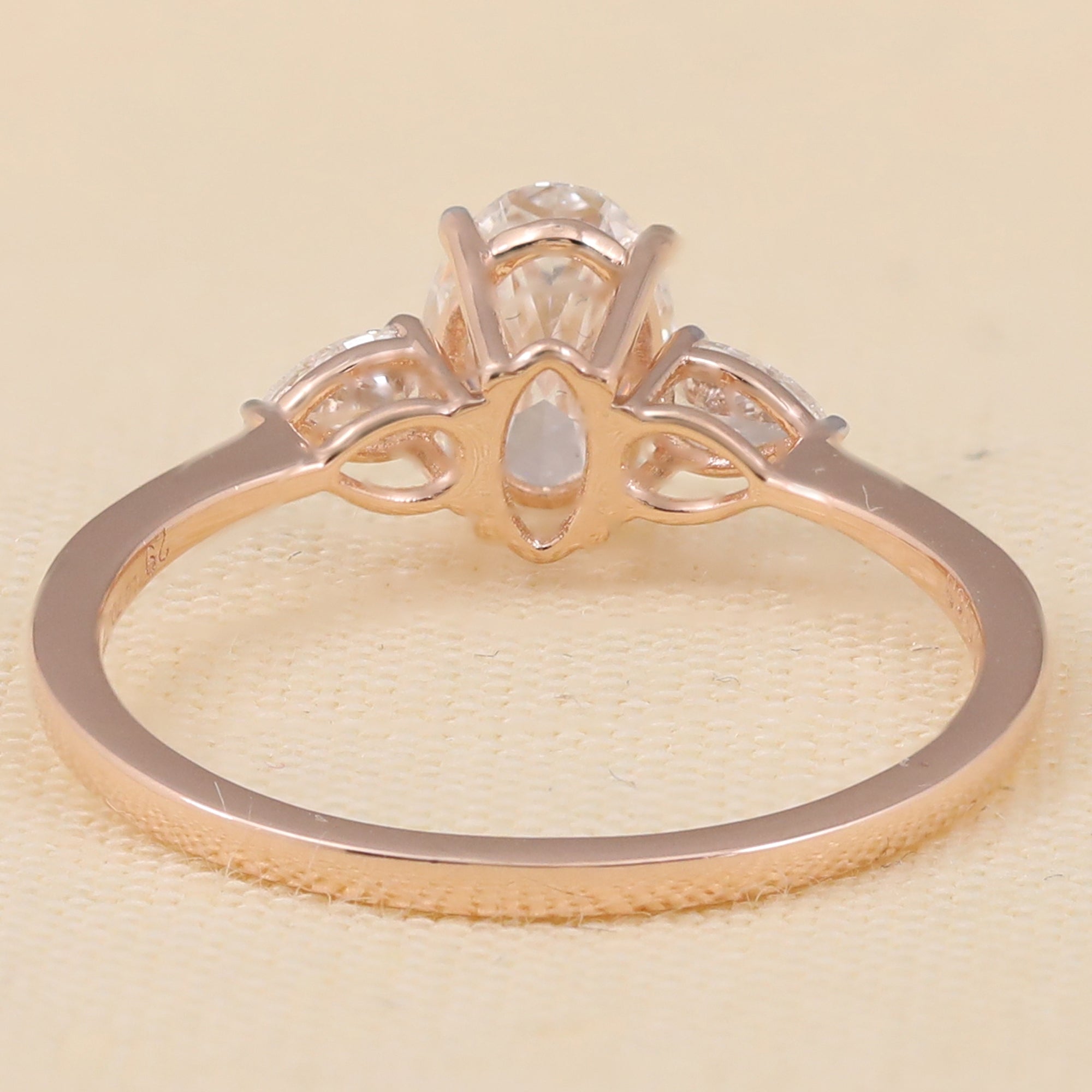 Delicate three-stone setting with an oval lab diamond and matching pear-cut side stones