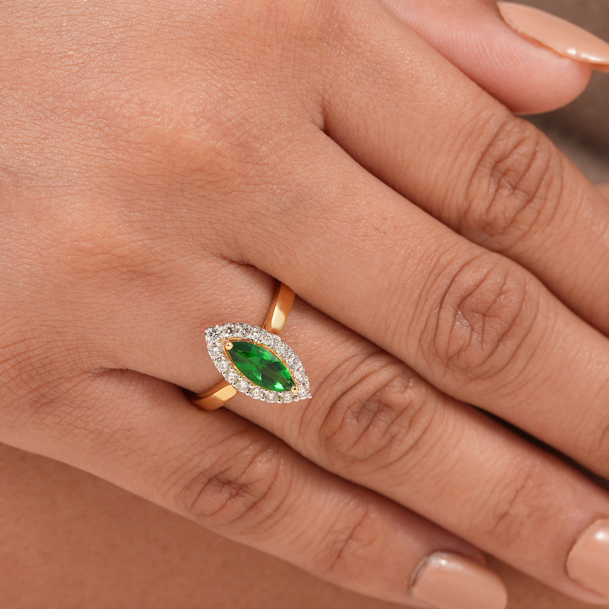 Green gemstone engagement ring featuring a brilliant diamond halo and polished gold band.
