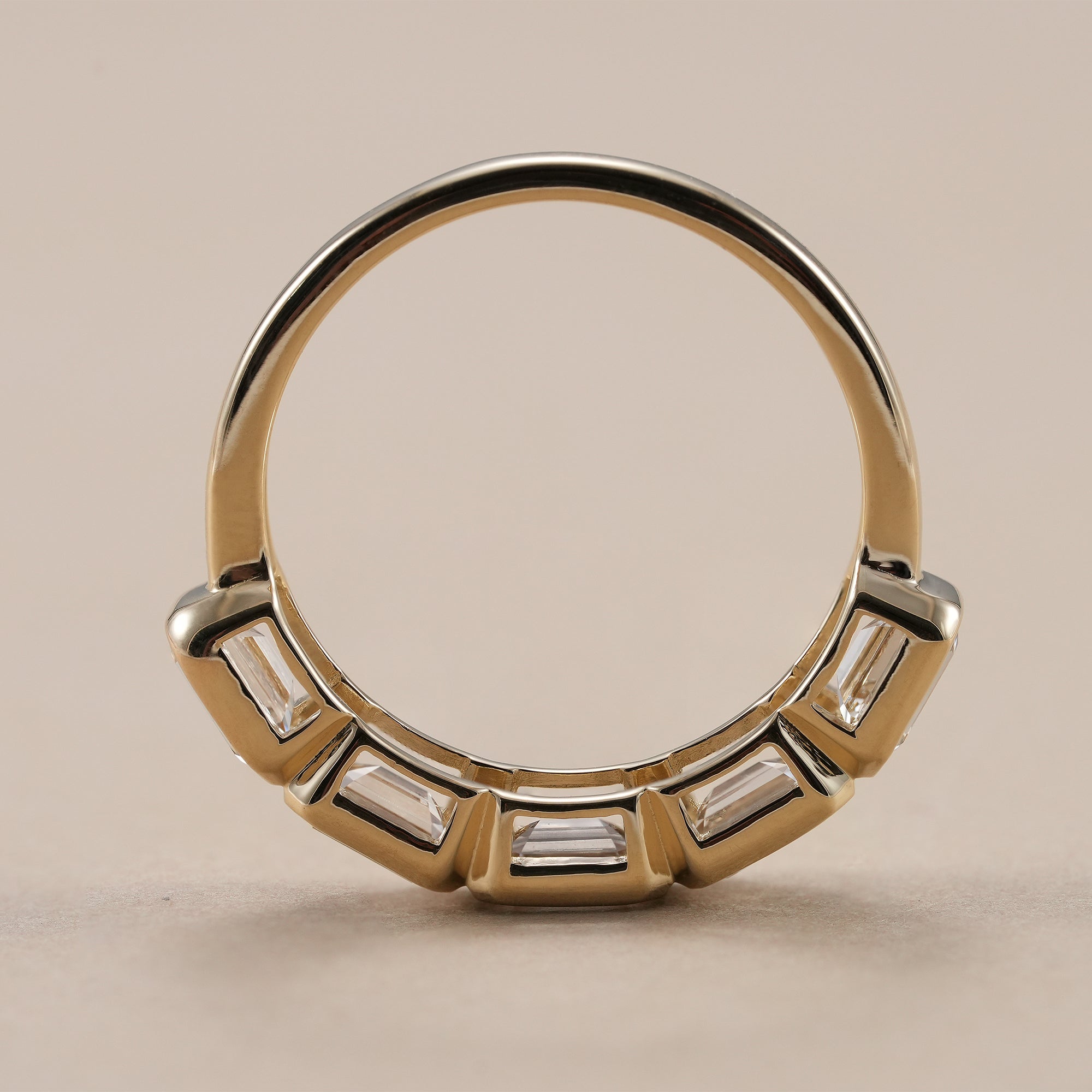 Modern bezel set emerald eternity ring for women.